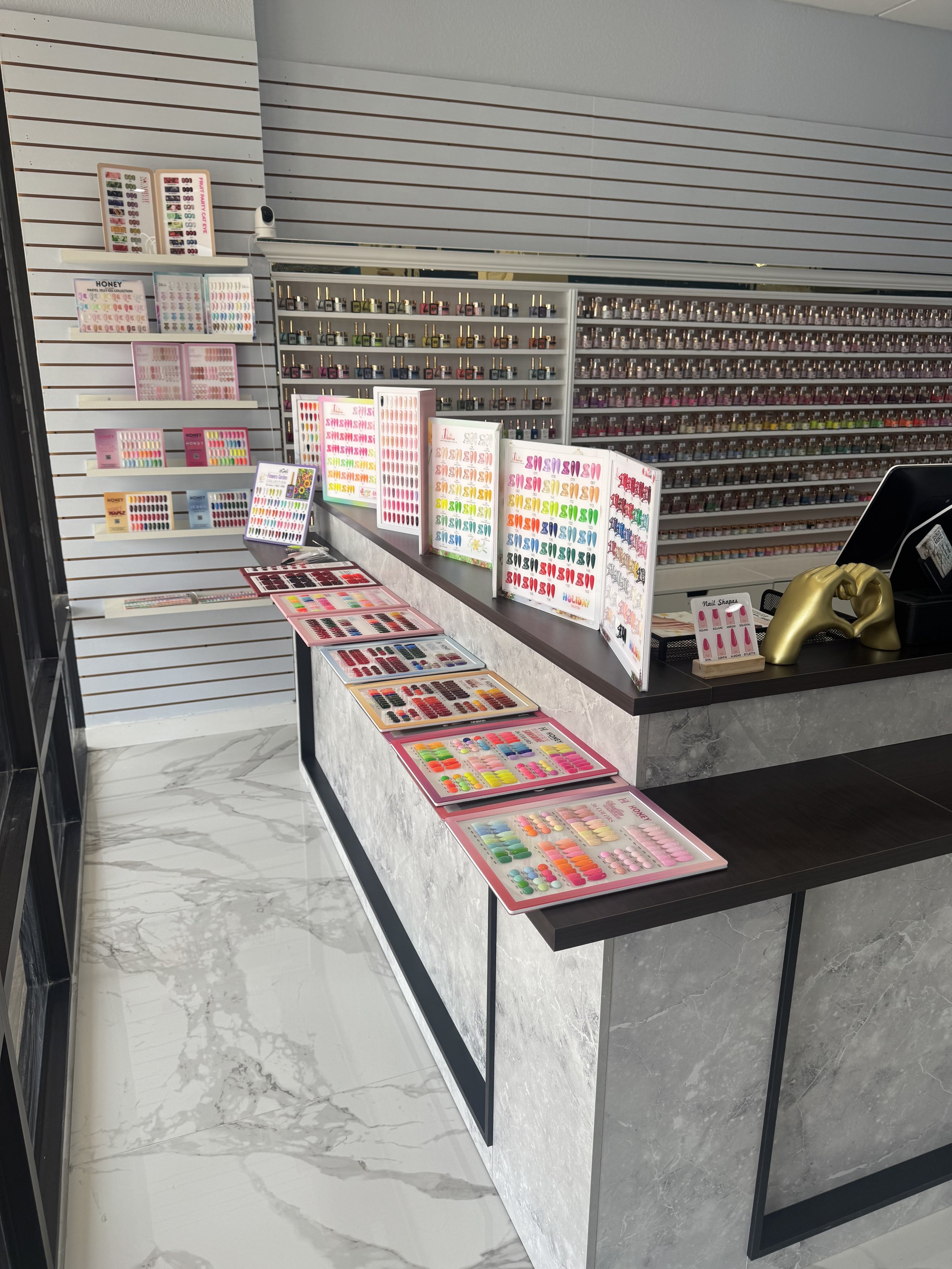Display of various colorful nail polish color samples and nail art decorations in a nail salon or beauty store.