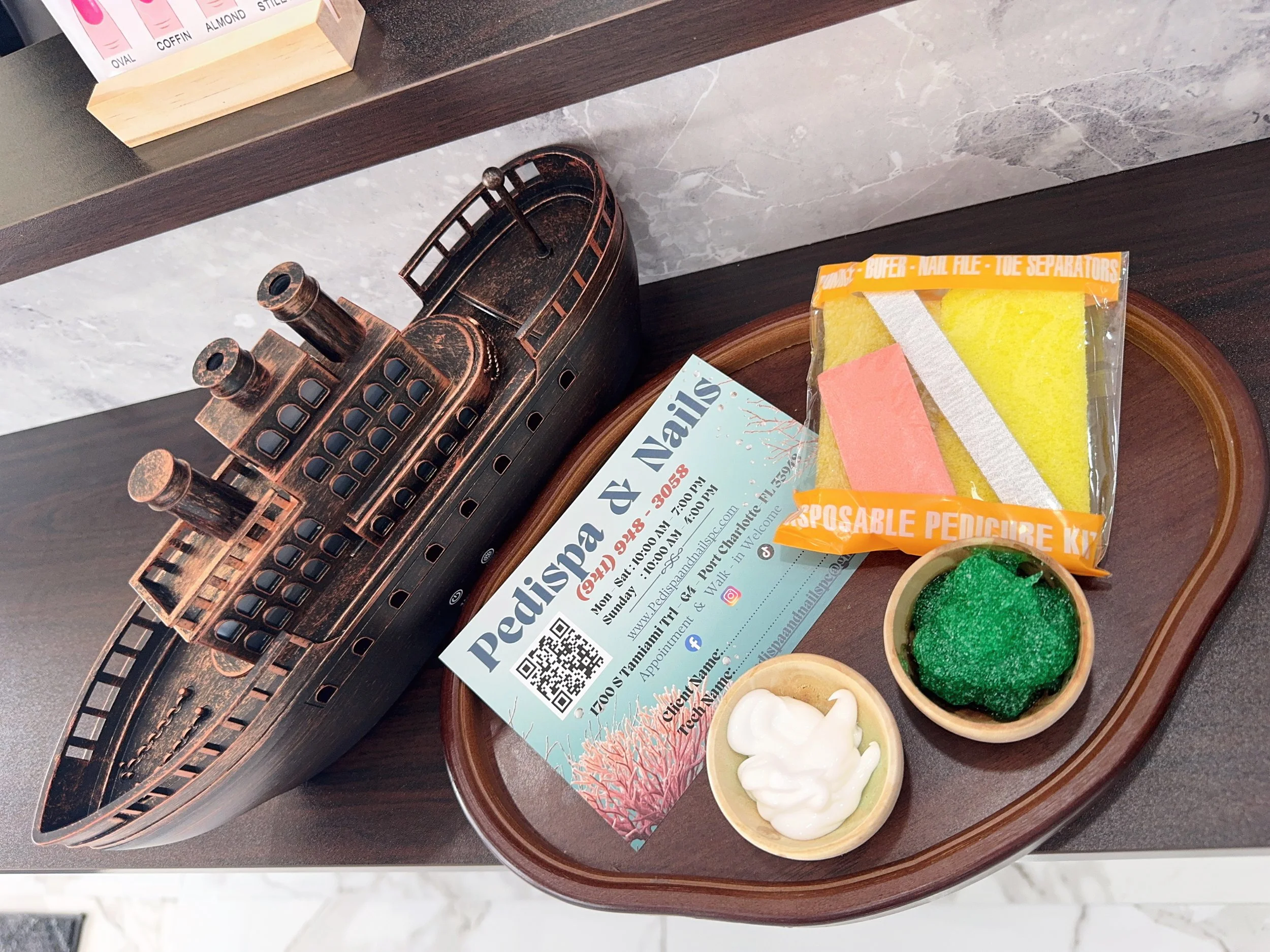 A wooden counter with small containers of colored crayon wax, possibly for making candle art or coloring, along with restaurant or business flyers, a turquoise magazine, and a yellow package labeled 'DISPOSABLE PENCIL BRUSH, NAIL FILE, TOE SEPARATORS