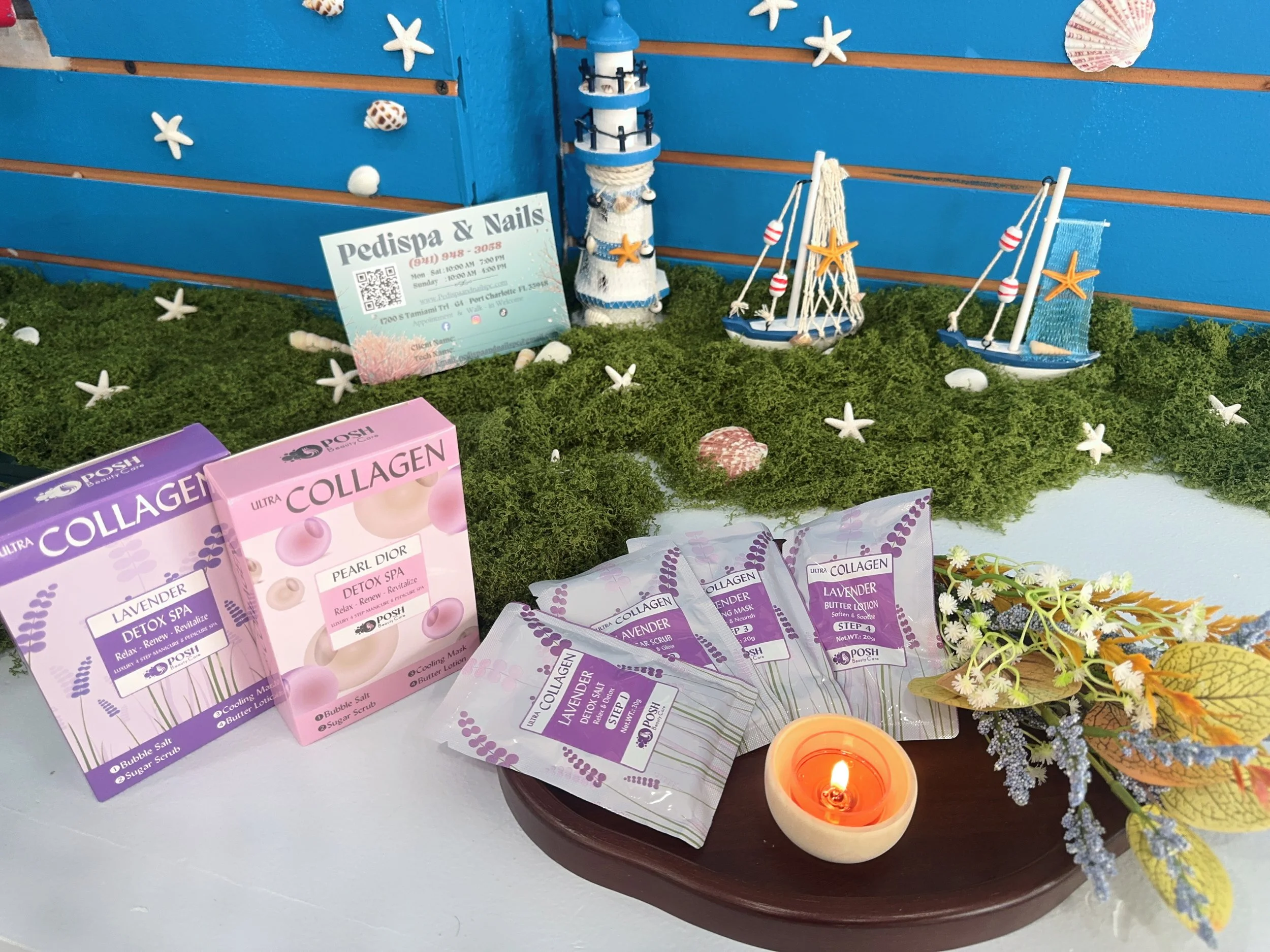 Display of collagen beauty products, candles, and decorative maritime-themed items like starfish and miniature sailboats on a table with moss and flowers.