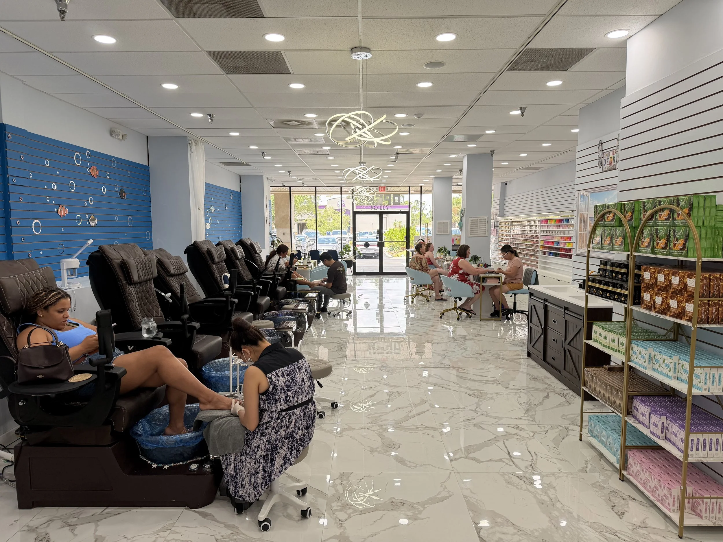 A salon inside a shopping mall with customers receiving pedicures, nail supplies on shelves, and modern ceiling lights.
