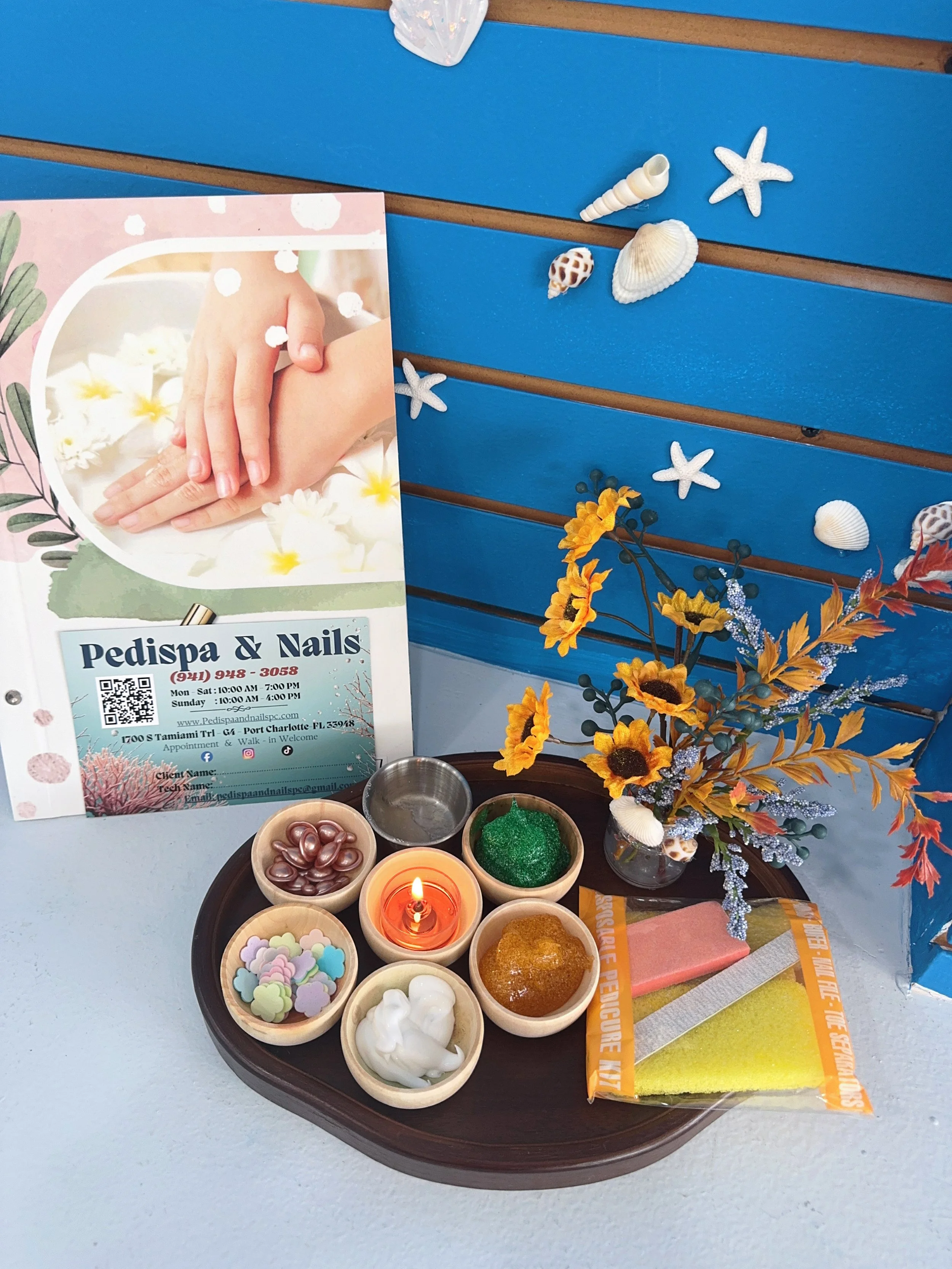 A display of small bowls with various decorative items and craft supplies, including colorful ceramic beads, glue, foam flowers, and candles, arranged on a tray on a table.