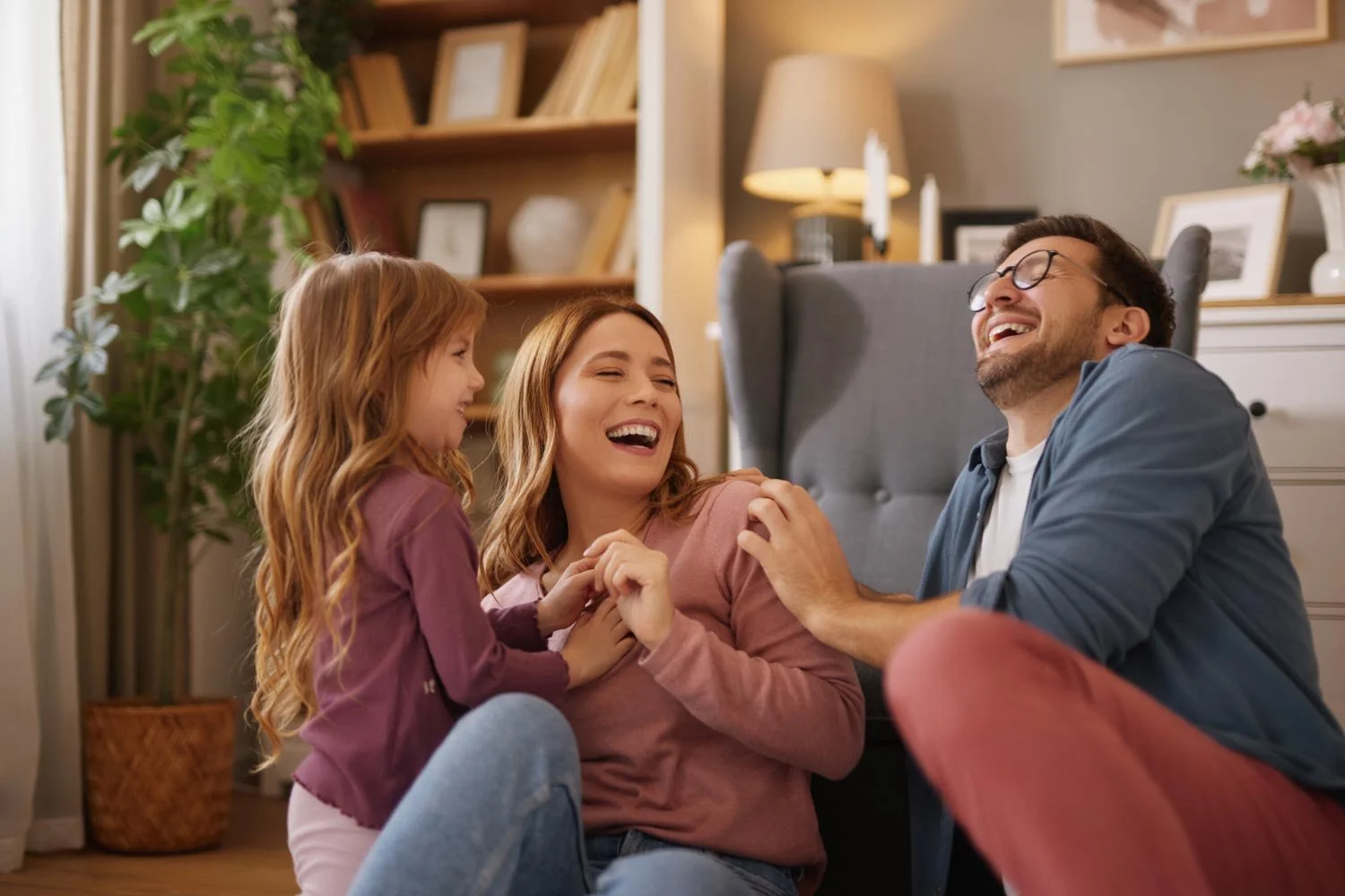 Family of three laughing and playing together at home.
