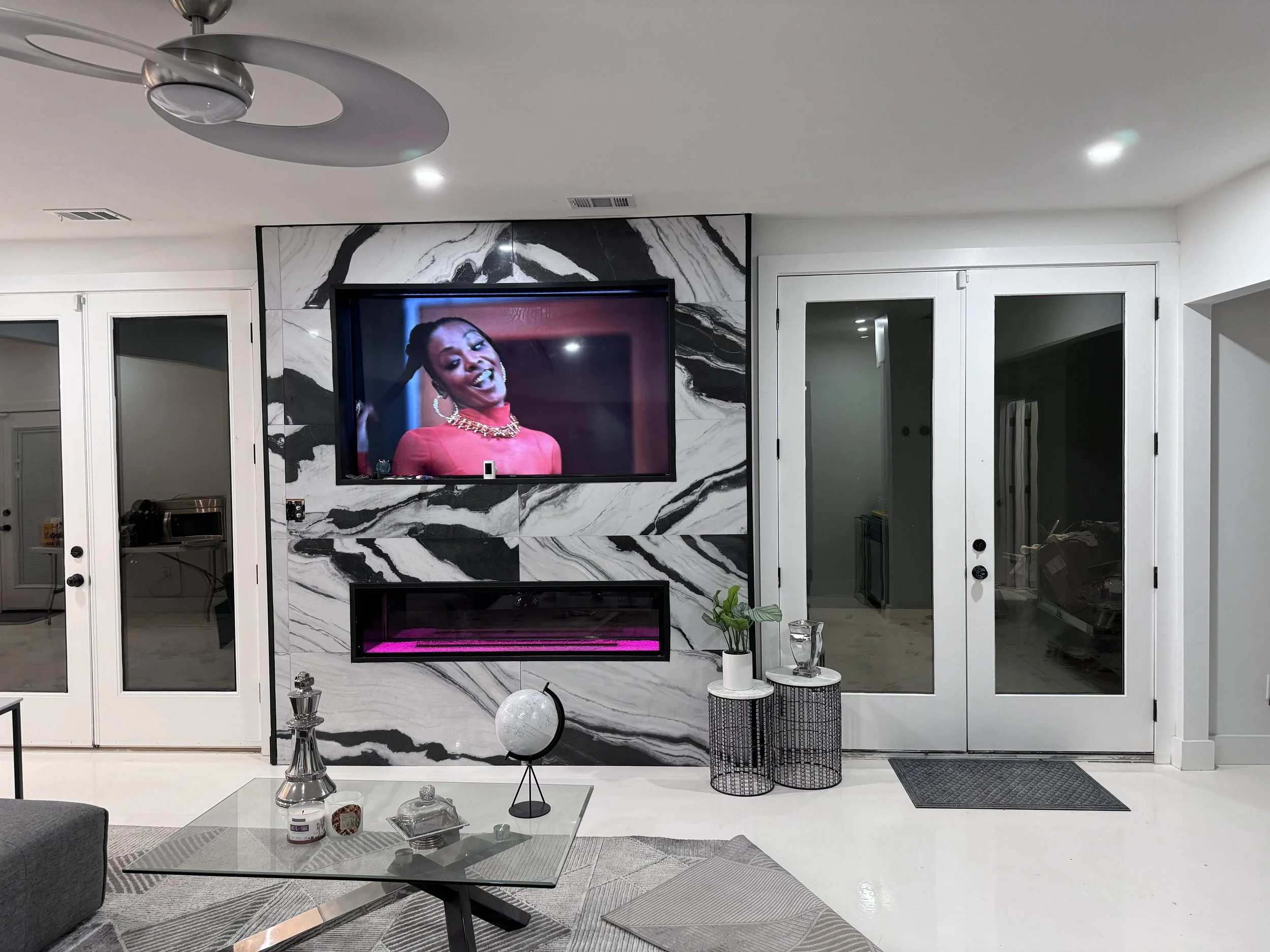 A basement custom build in  fireplace, a wall-mounted TV , and custom epoxy floors, and various decorative items including plants, a globe, and candles in Douglasville Georgia.