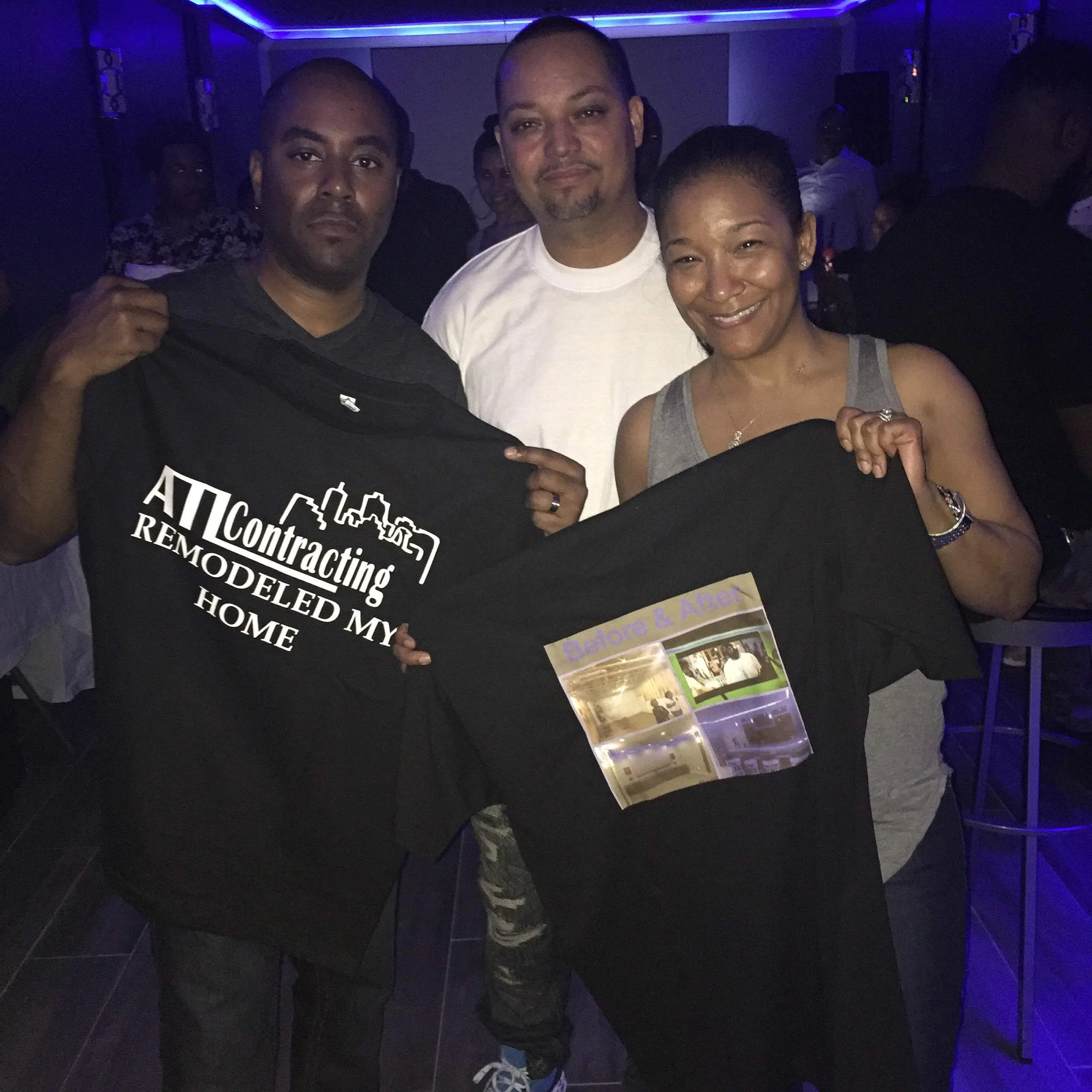 Happy clients giving a great review after they basement finish by ATL Basement Solutions , Craig Render giving them Company shirts with logos to show his gratitude
