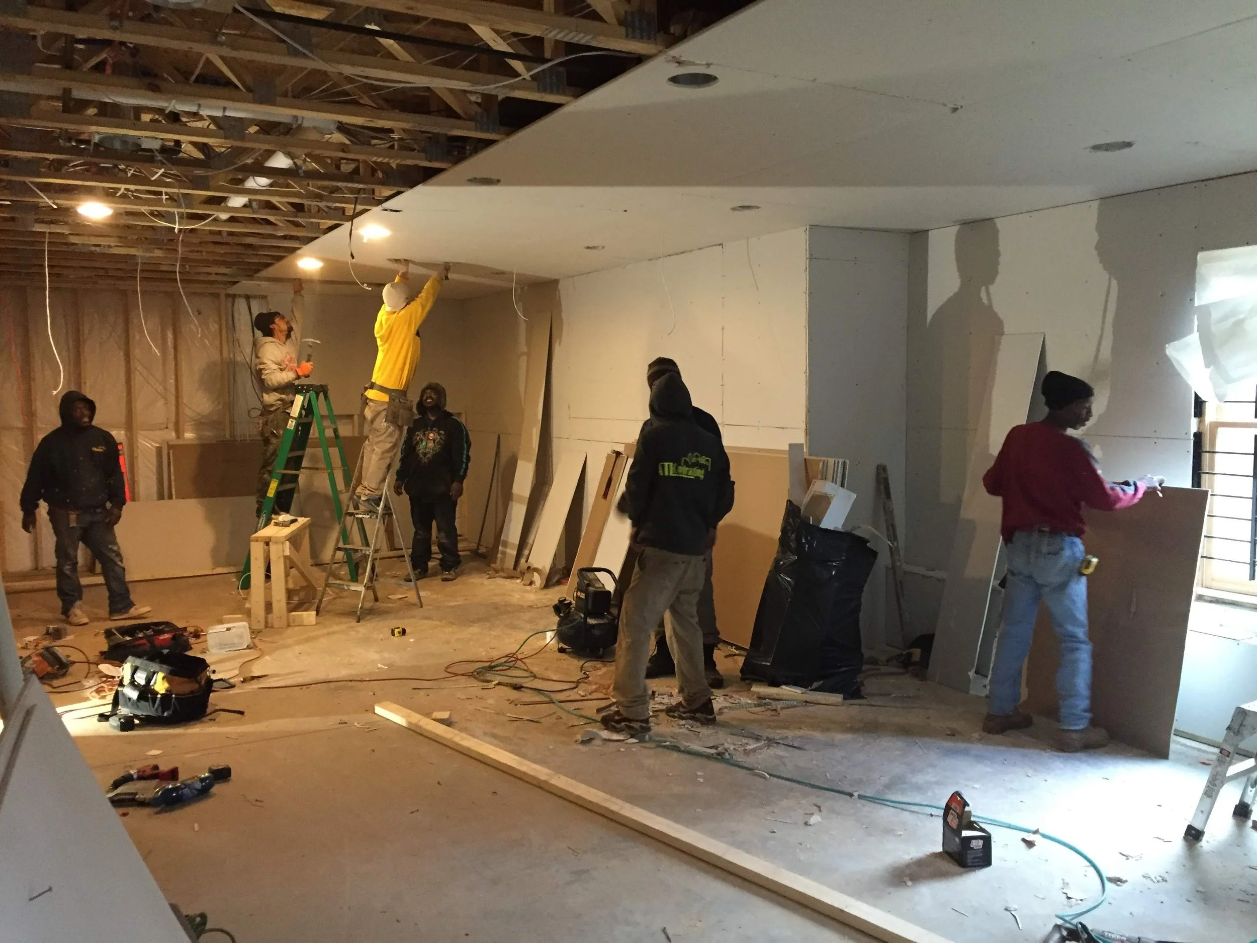 Atl Basement Solutions Construction workers installing drywall on the ceiling in a basement under renovation in Fairburn georgia