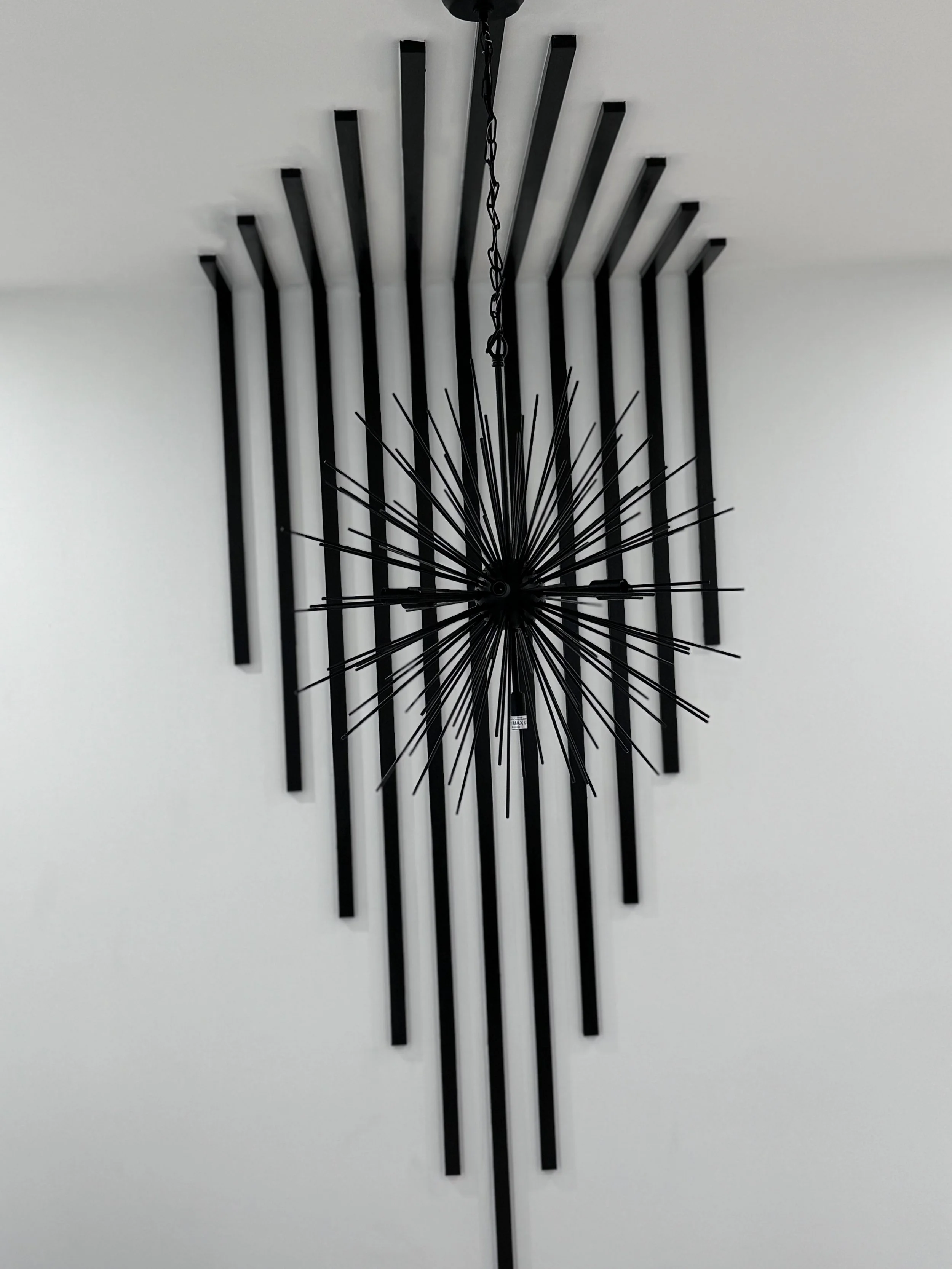 Modern black light fixture with radiating black rods on a white wall. sleek and modern design in Douglasville Ga.
