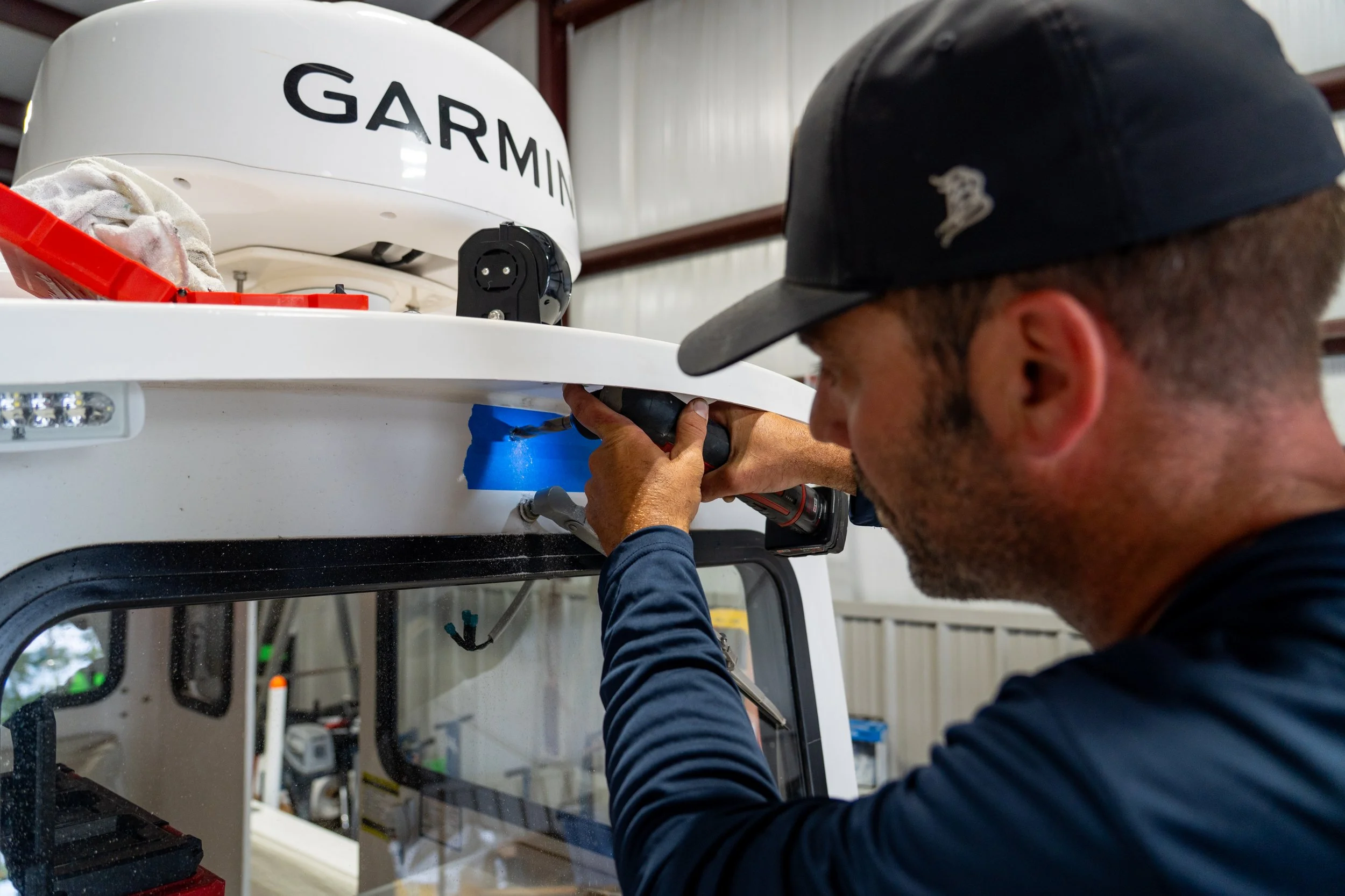 A man is working on a Garmin device mounted on a vehicle, possibly a drone or robotic equipment, inside a workshop or garage.