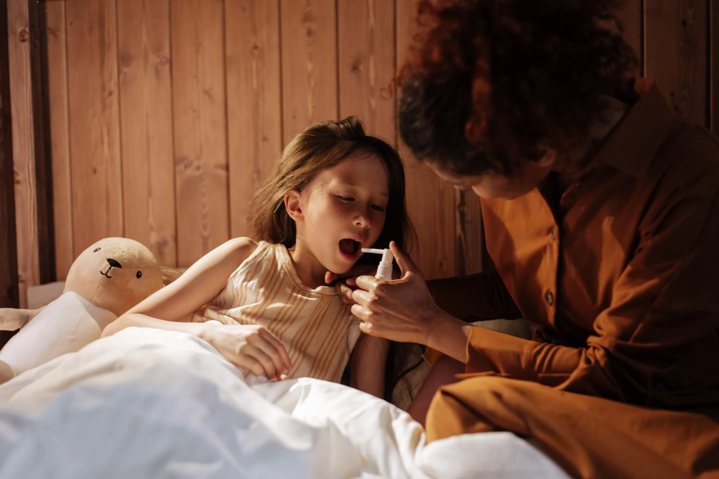 Mom taking sick daughters' temperature in bed