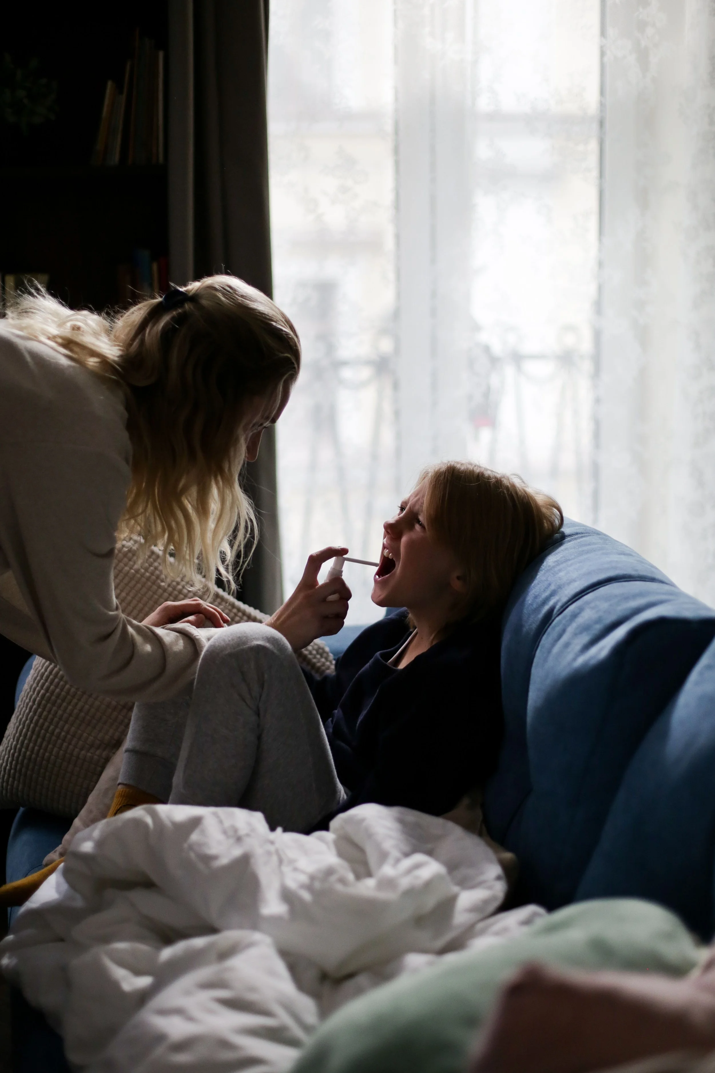 Mom spraying medicine into child's mouth