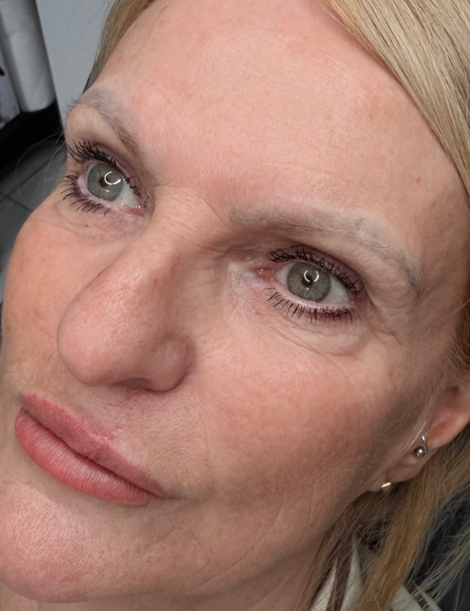 Close-up of a woman's face showing her eyes, nose, lips, and a facial piercing with a small ball on her lower lip.