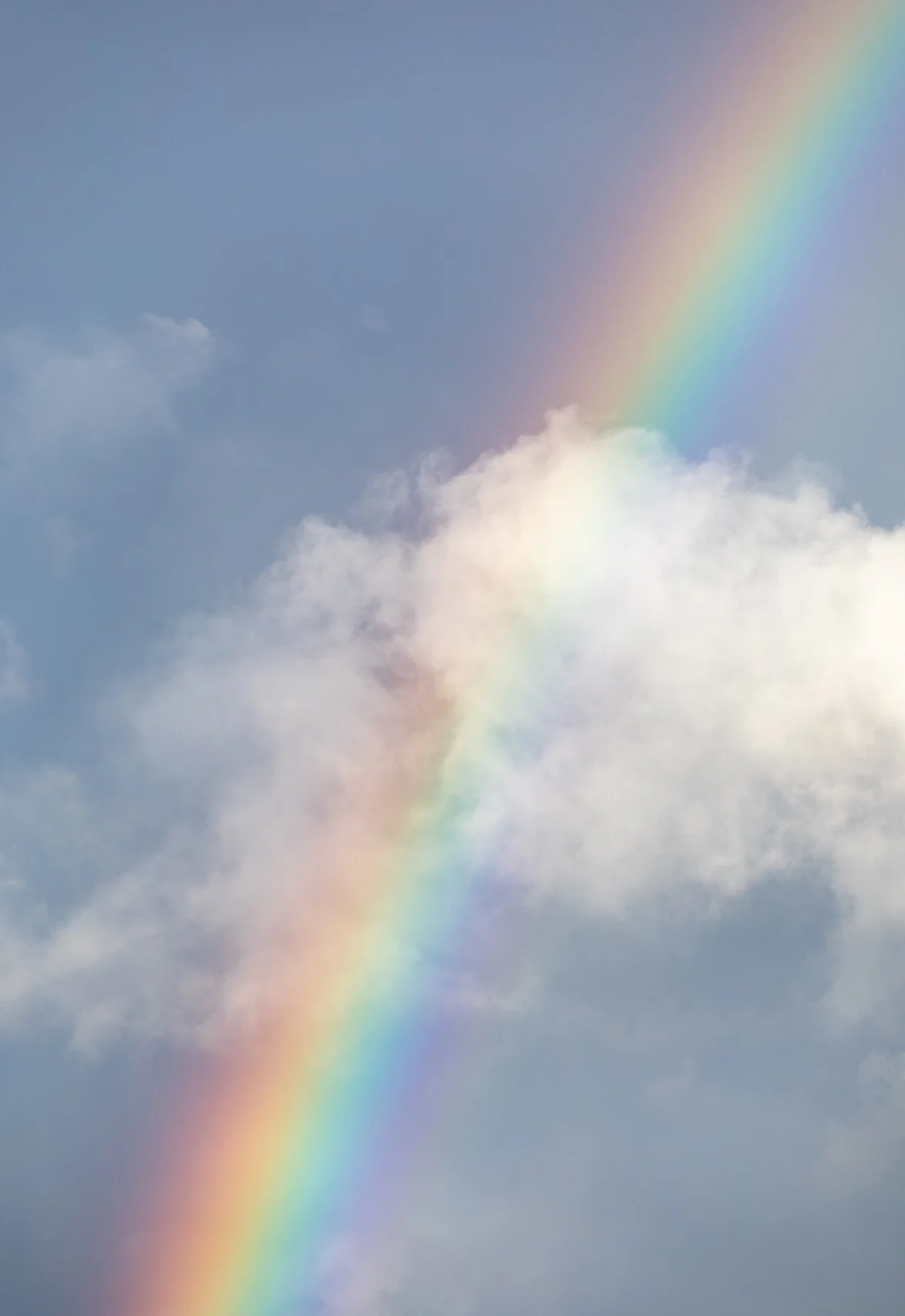 A rainbow arching through a sky with clouds.