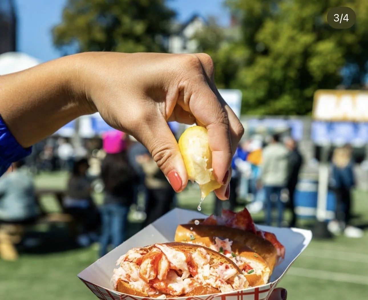 hand squeezing a lemon onto a lobster roll