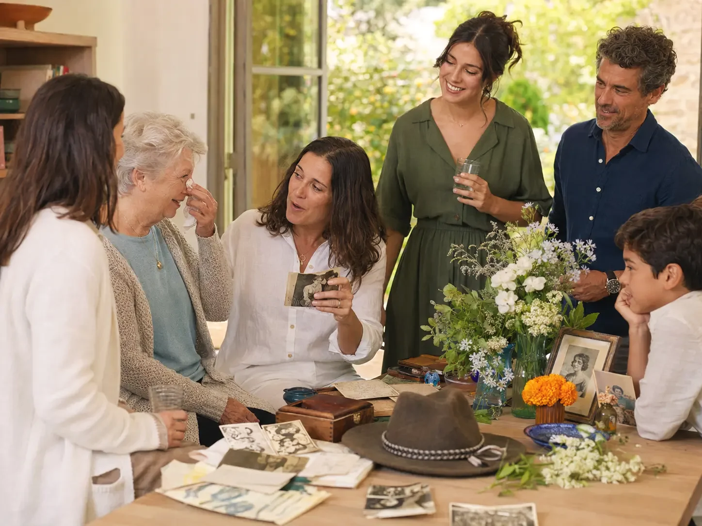 A group gathered around a table sharing stories, photographs and meaningful personal objects.