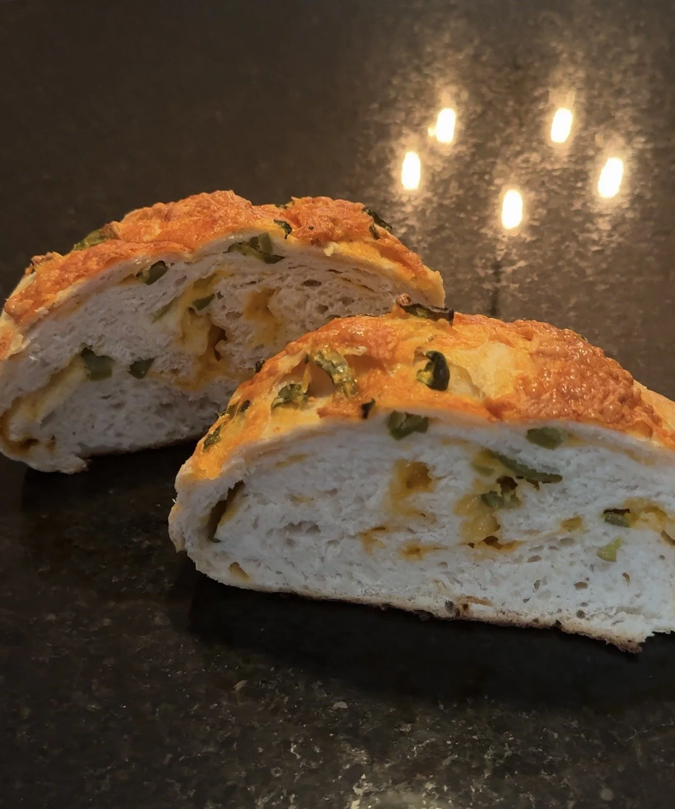 Freshly baked jalapeño cheddar sourdough bread with a crisp golden crust, melted cheddar cheese, and diced jalapeños baked throughout the loaf.