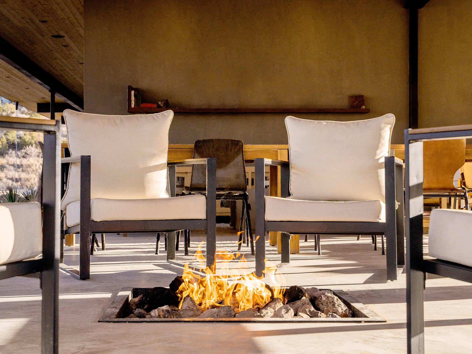 two chairs by a fire pit under The Lodge roof 