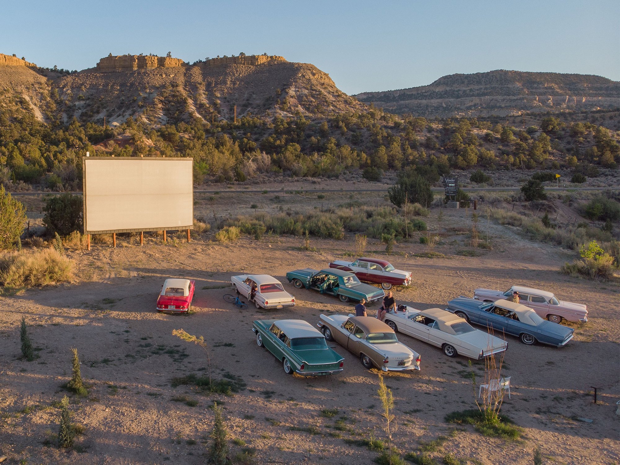 Ofland Escalante Drive-in Theater with vintage cars for seating and a view of rocky cliffs and hills on the background 