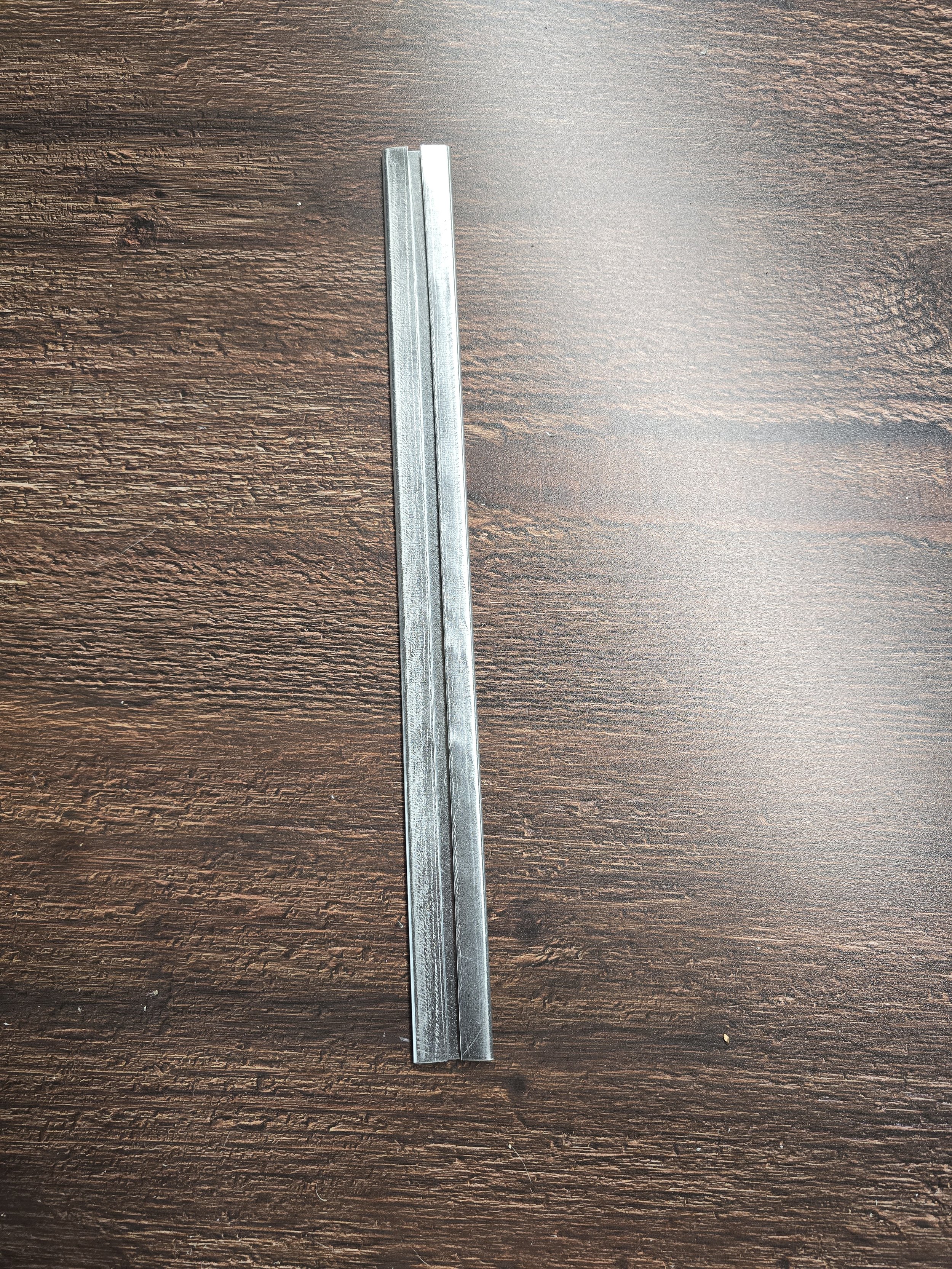 A metal chisel placed on a dark wooden surface.