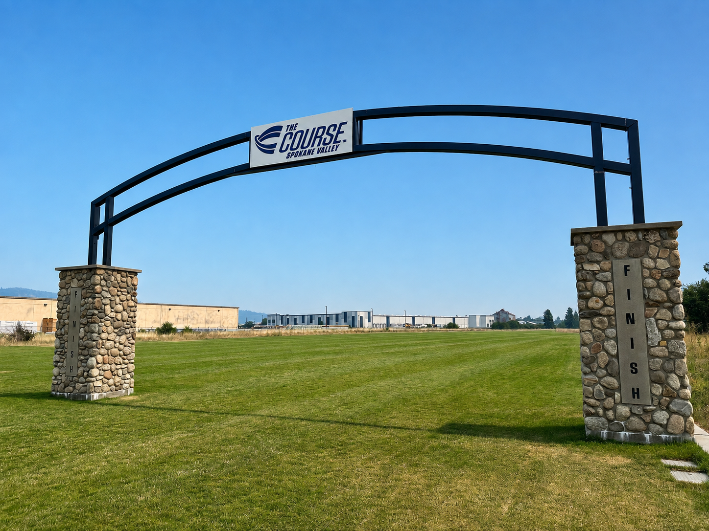 Stone-and-steel finish-line arch over turf at The Course in Spokane Valley