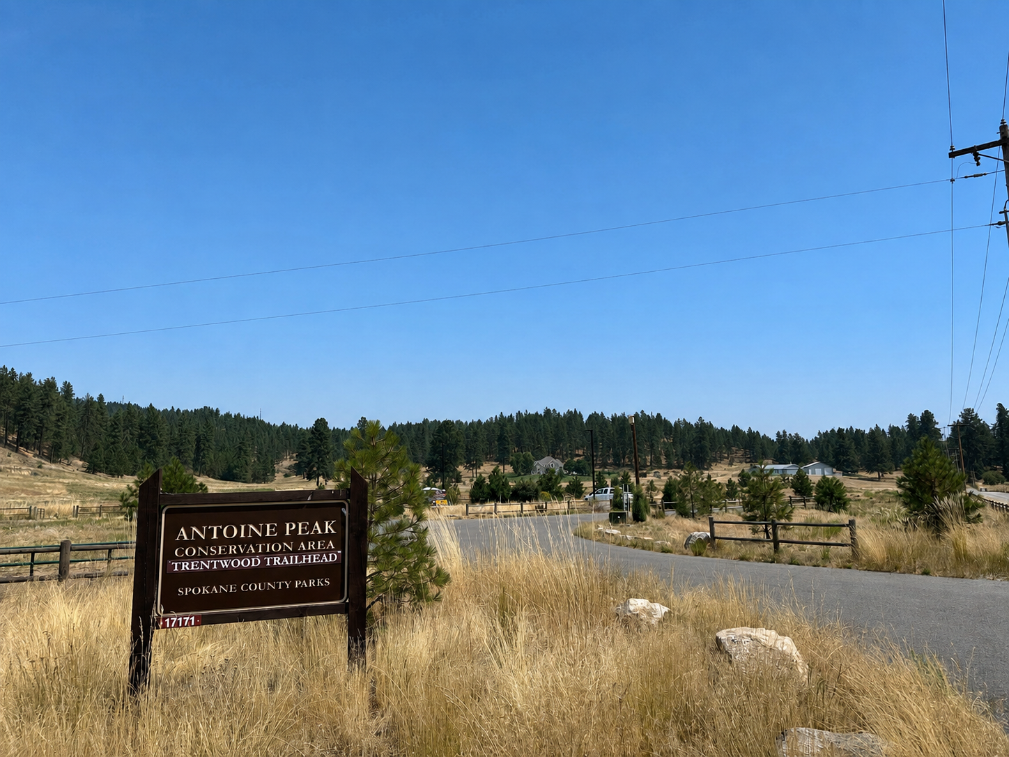 Trentwood Trailhead sign beside a paved road and dry meadow at Antoine Peak Conservation Area