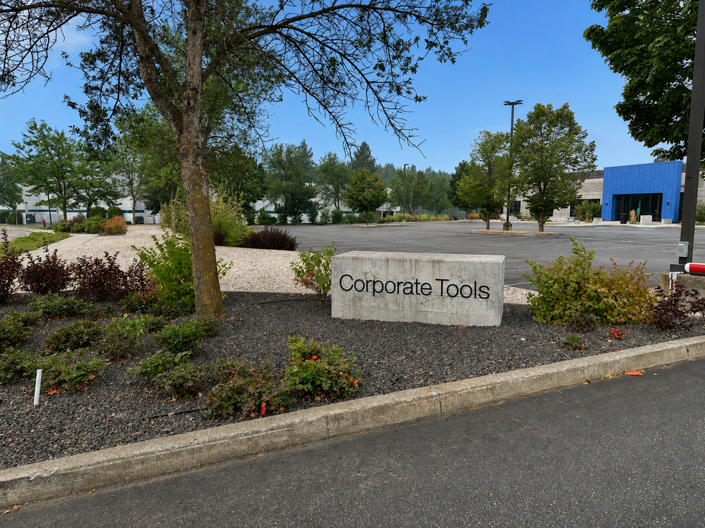 Corporate Tools monument sign framed by trees, shrubs, and rock-mulched planting beds