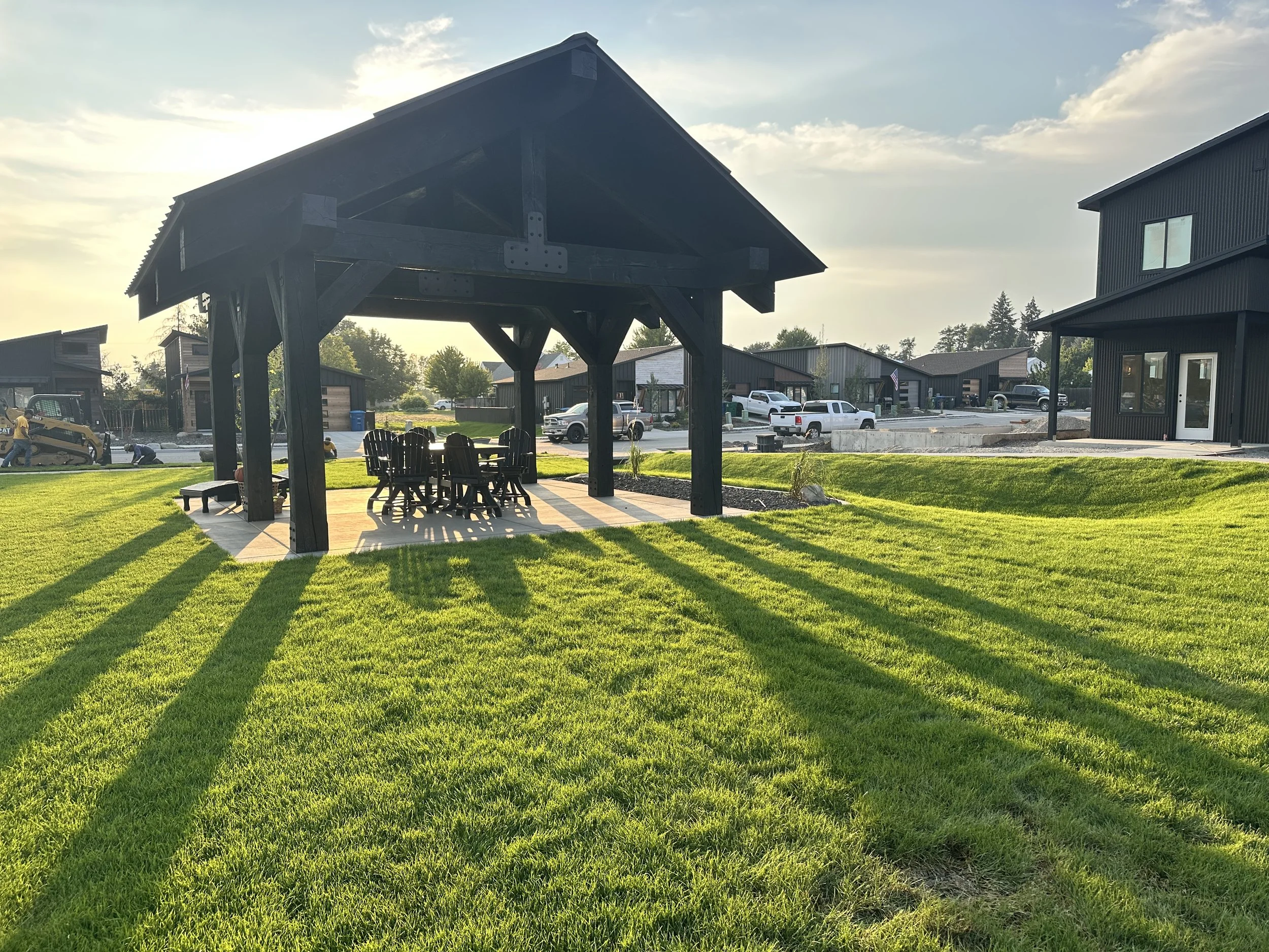 Neighborhood park lawn with a covered picnic shelter and nearby homes