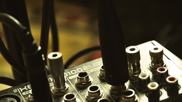 Close-up of an audio mixer or soundboard with various input jacks and cables connected.