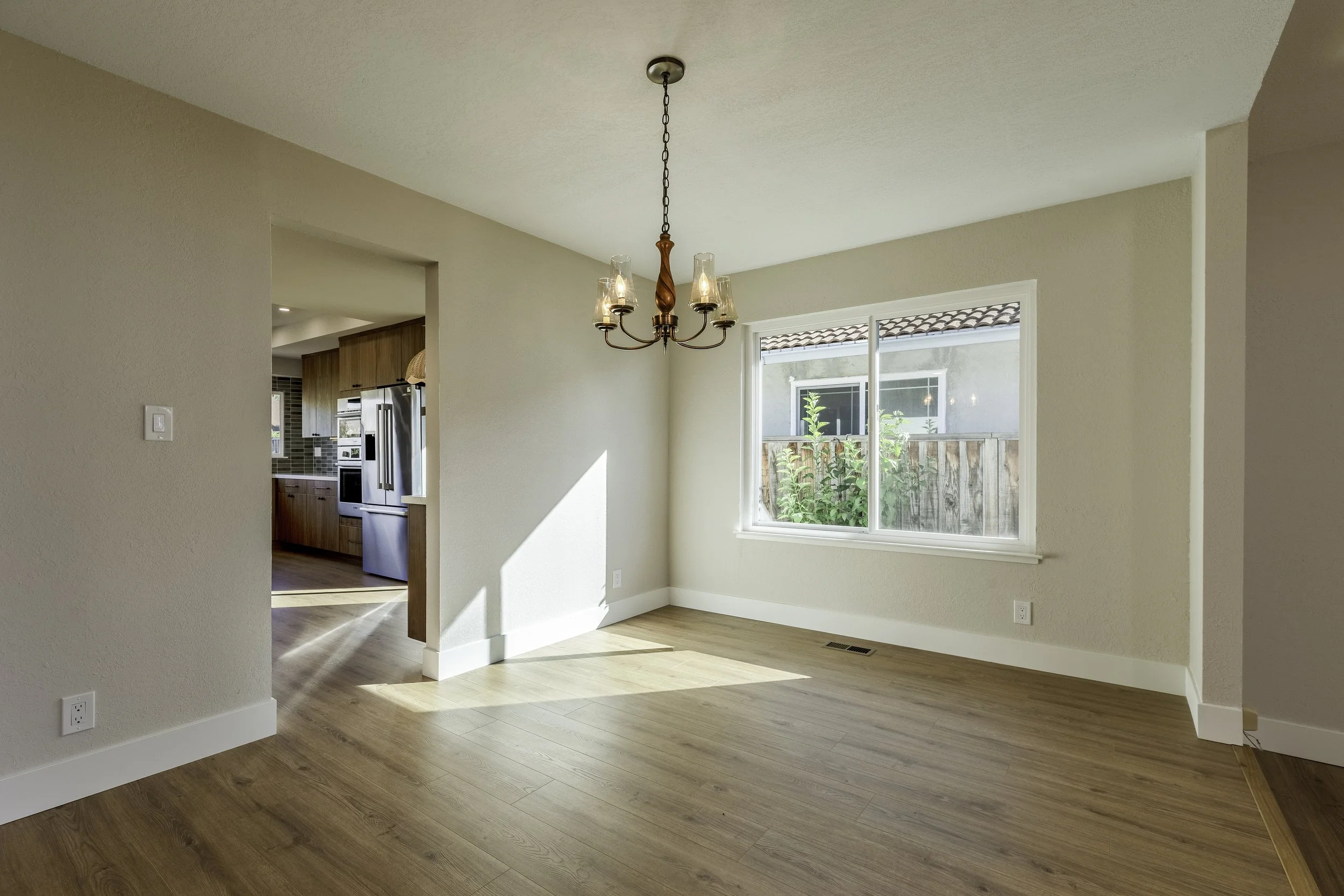 Empty room with hardwood floors, a window, and a chandelier