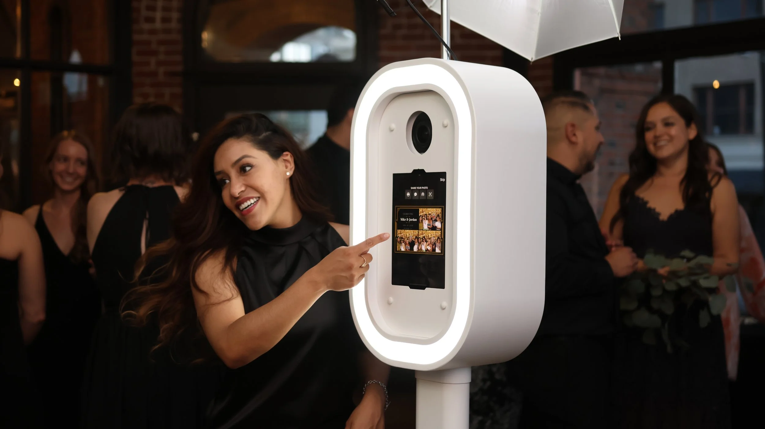 Guest using a white digital photo booth at an indoor event venue.