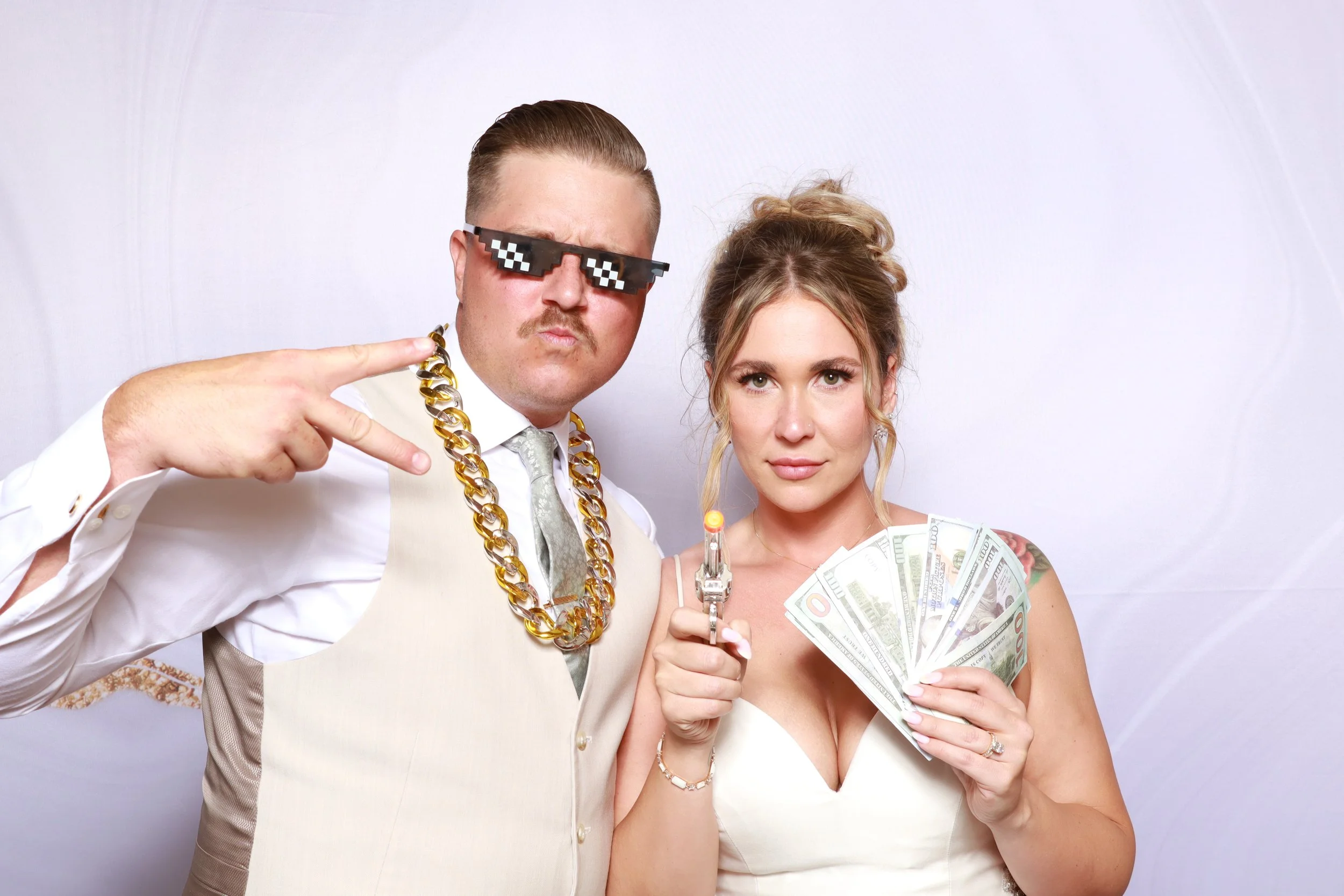 Bride and guest posing with playful accessories for a wedding photo booth portrait.