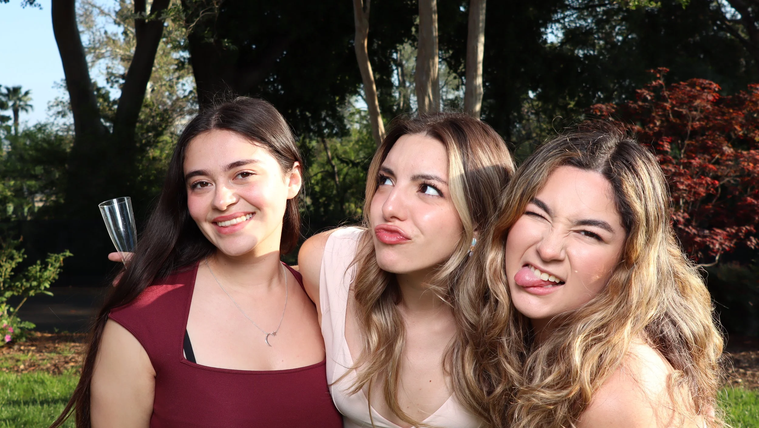 Three women posing together for an outdoor photo booth portrait.