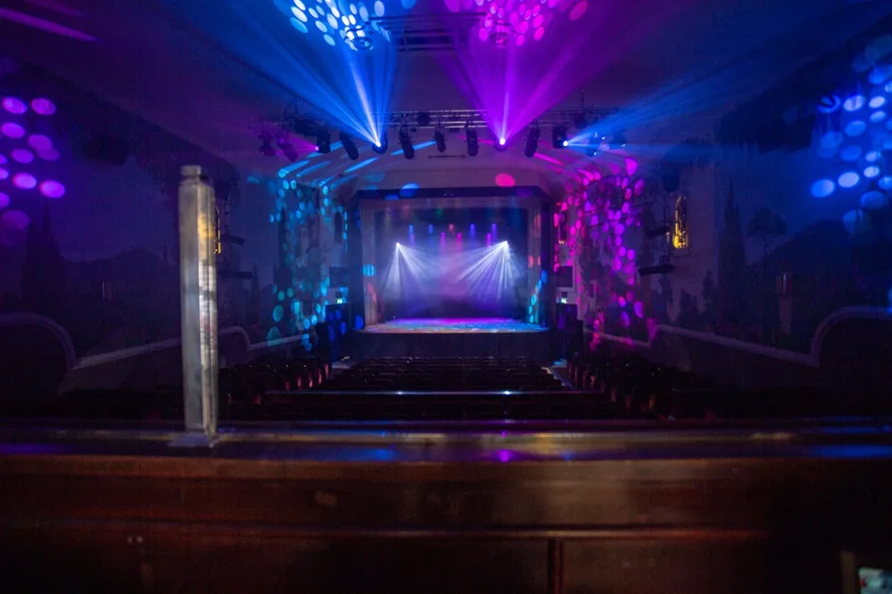 Empty theater stage with colorful lights and spotlights creating a vibrant atmosphere.