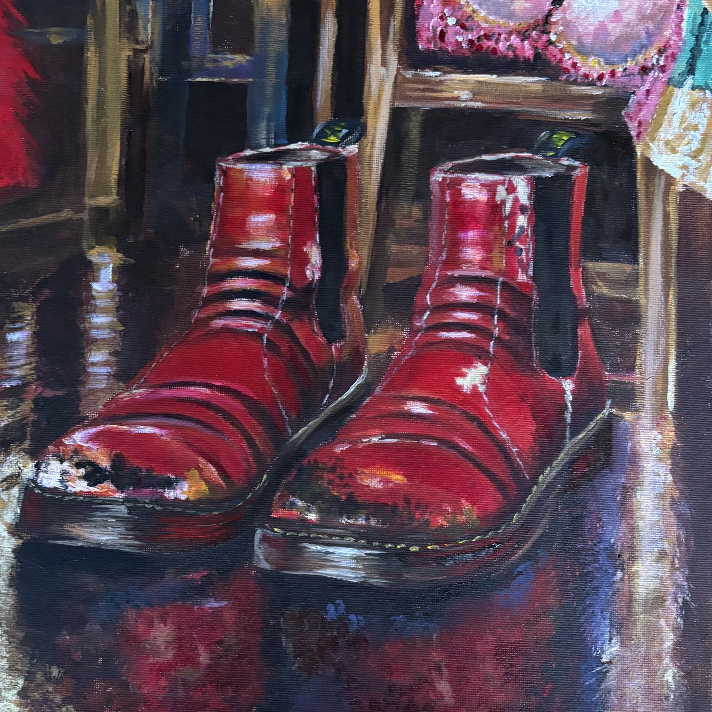 Painting of worn red Chelsea boots with scuffed toes on a reflective dressing-room floor, beneath a wooden chair draped with a pink costume.
