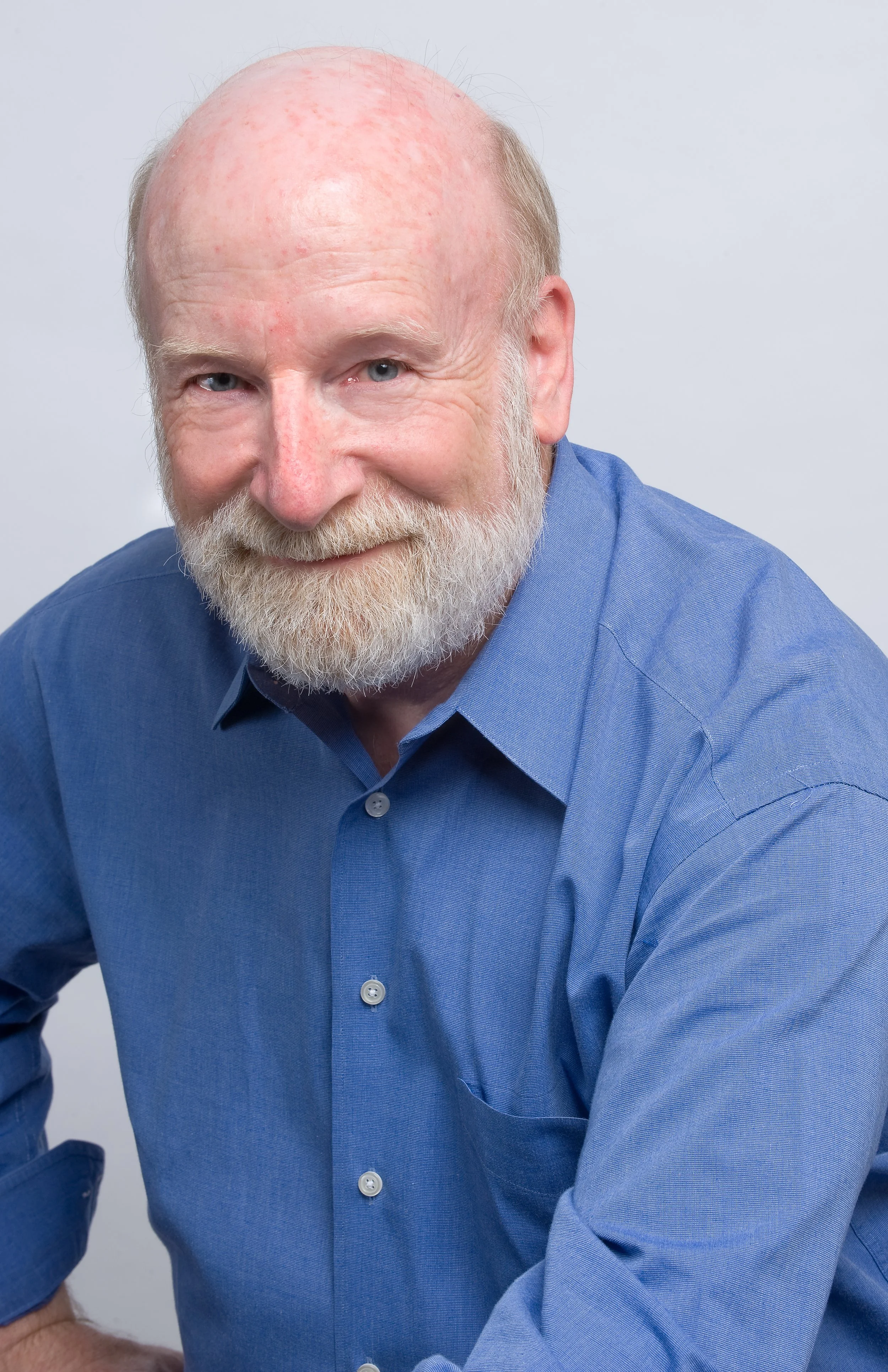 William smiling and leaning toward the camera, wearing a blue shirt