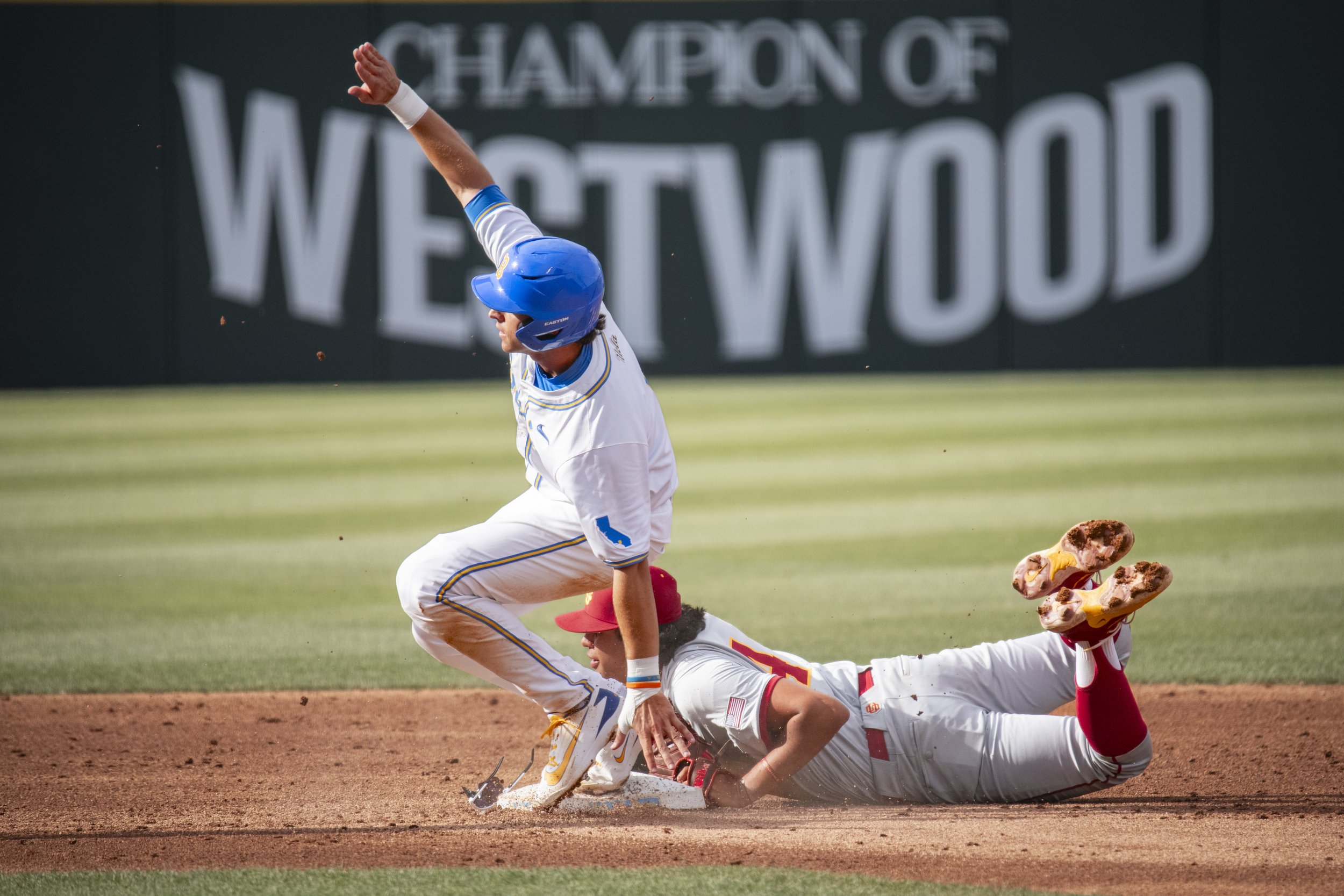A baseball player sliding into home plate while another player attempts to tag him out during a game.