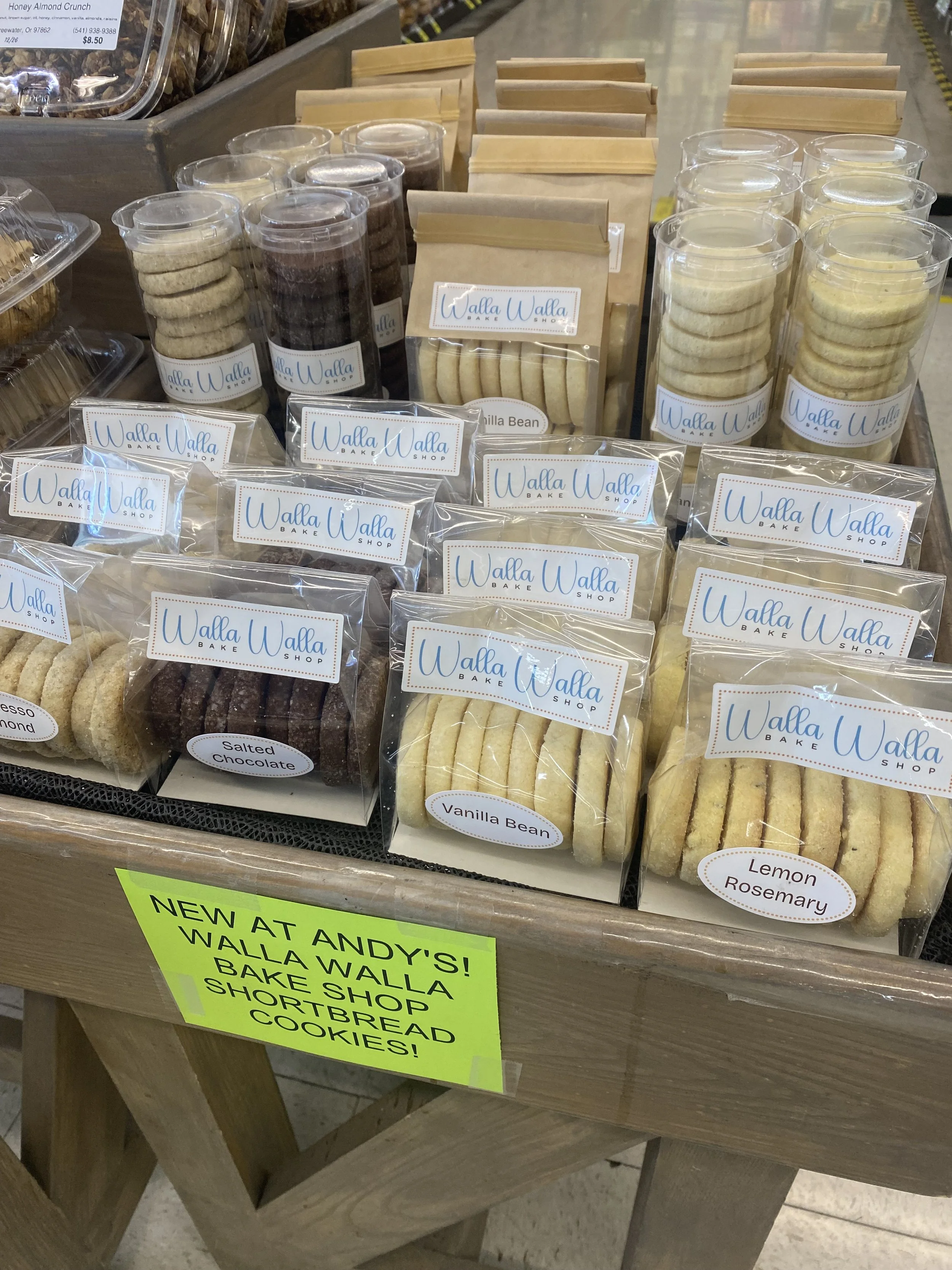 Display of packaged cookies at Walla Walla Bake Shop, including vanilla bean, lemon rosemary, and salted chocolate cookies in clear plastic bags and cylindrical containers.
