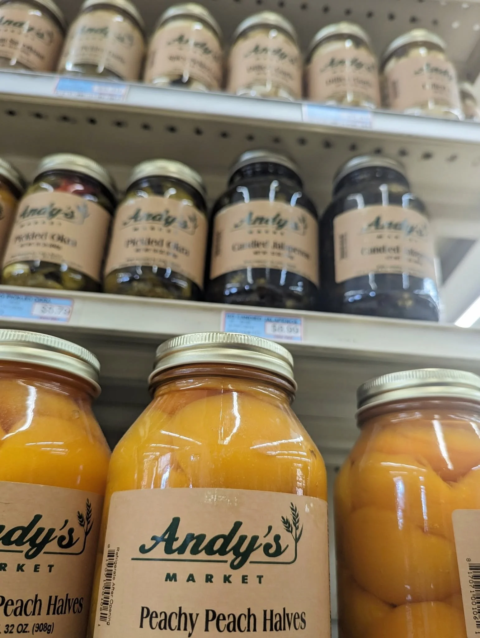 Jars of Andy's Market Peachy Peach Halves canned peaches on store shelf.