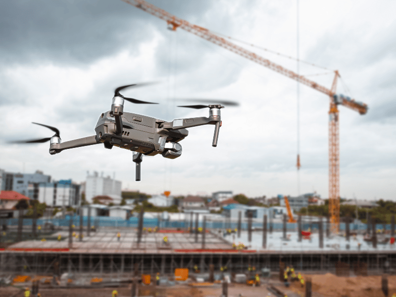A drone flying over a construction site with a crane in the background.