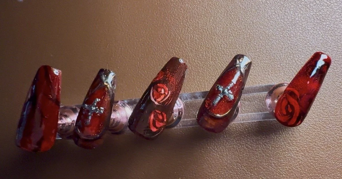 Set of red and black swirl-patterned acrylic nails on a clear display stand.
