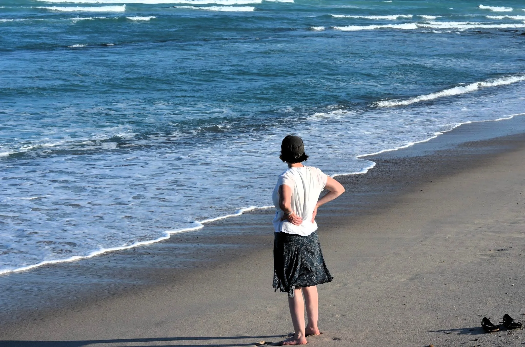 Woman standing beside the ocean on a quiet beach