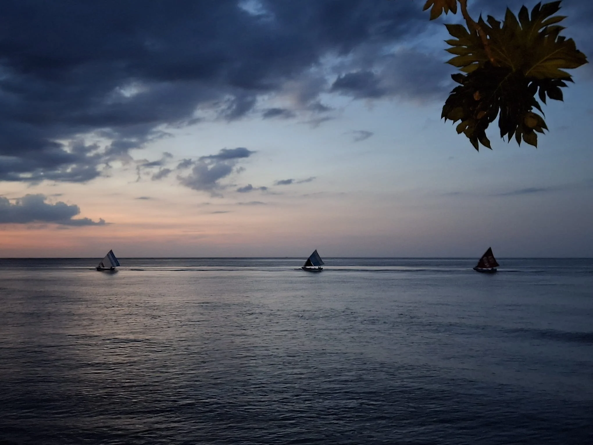 Three traditional sailboats crossing the sea at sunset in Amed, Bali, Indonesia
