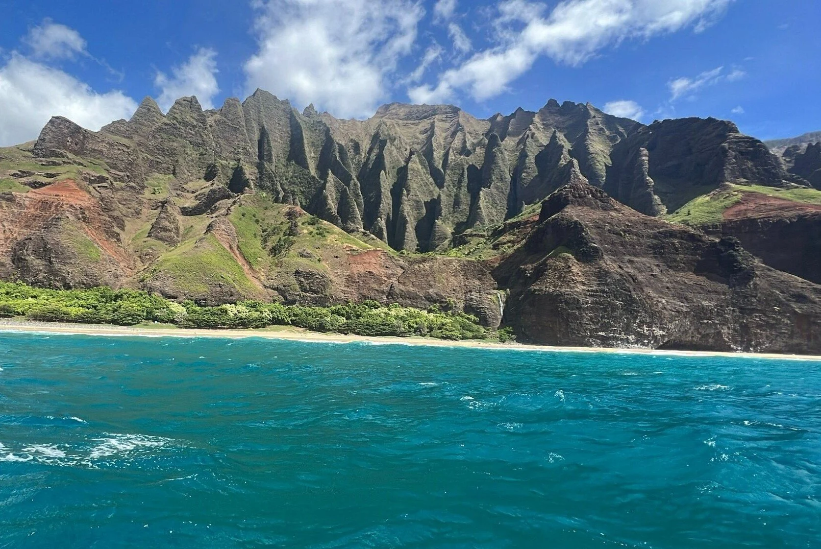 Dramatic green cliffs and turquoise ocean along the Na Pali Coast in Kauai, Hawaii