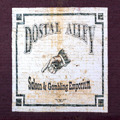 Vintage Dostal Alley Saloon & Gambling Emporium sign painted on a brick wall in Central City, Colorado