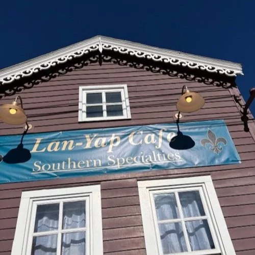 Exterior of Lagniappe Cafe with blue restaurant sign on a historic building in Central City