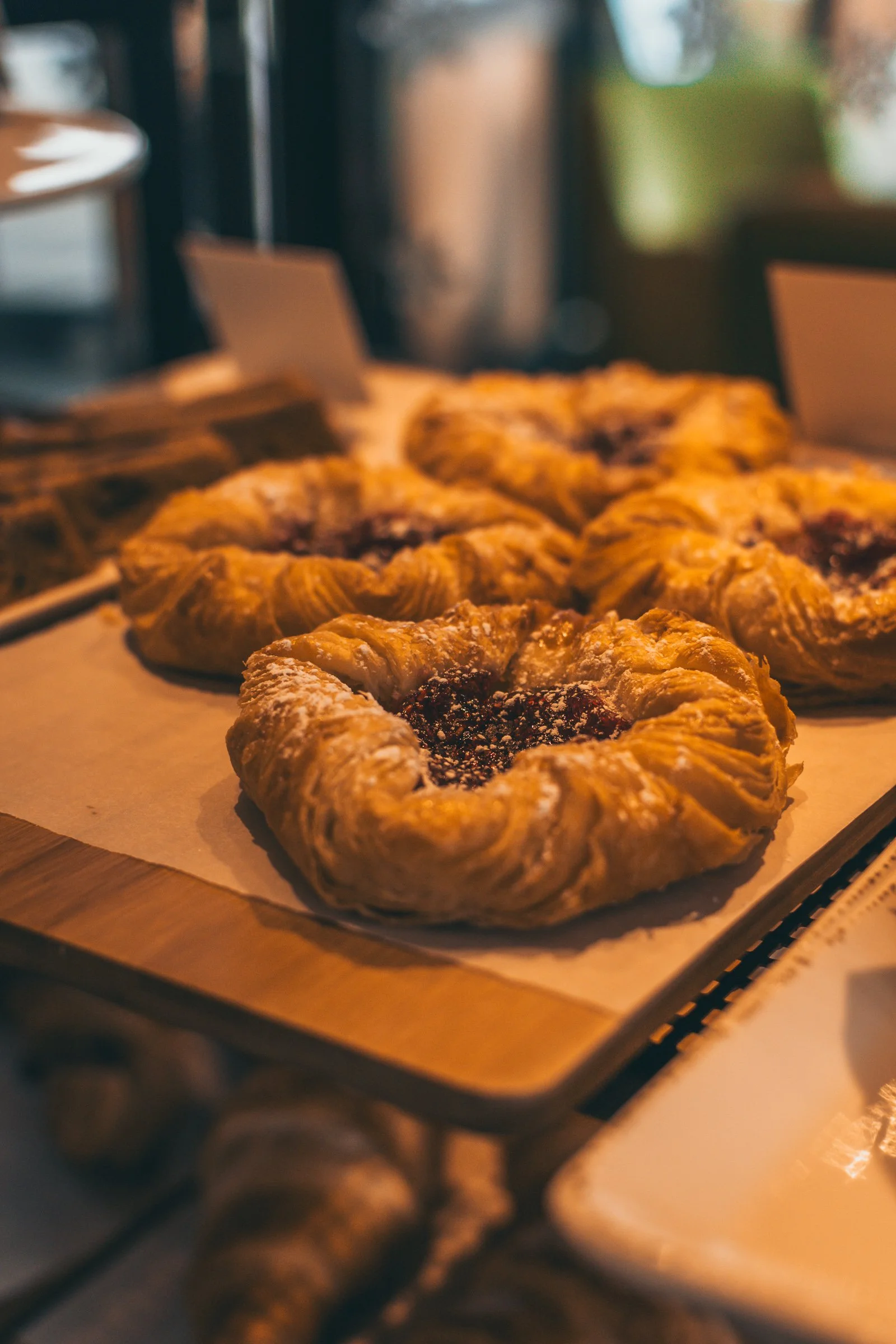 Puff pastry pastries with dark fruit jam in the middle, on parchment paper, in an oven.