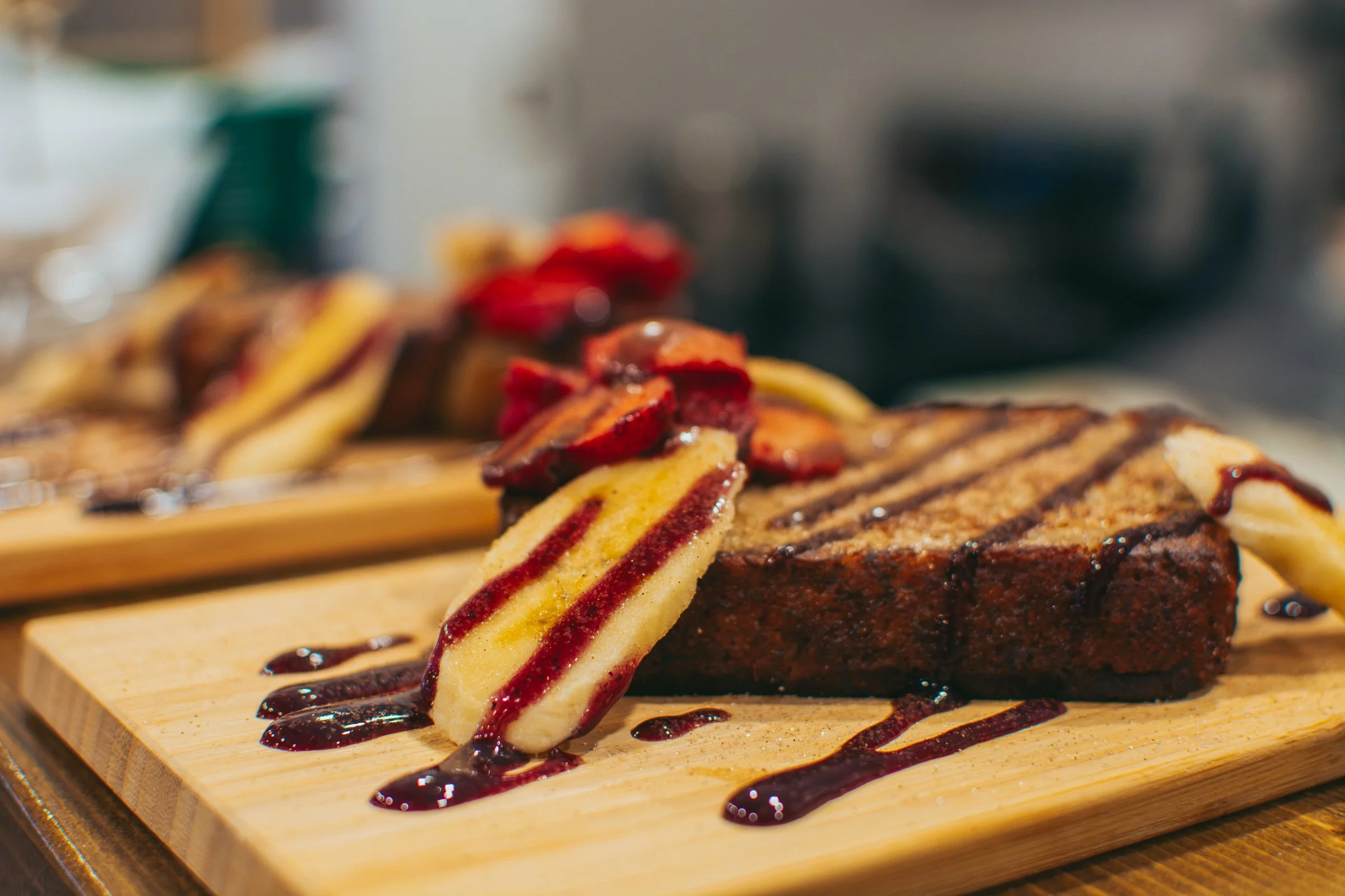 Slices of grilled steak and grilled vegetable skewer with balsamic glaze served on a wooden board.
