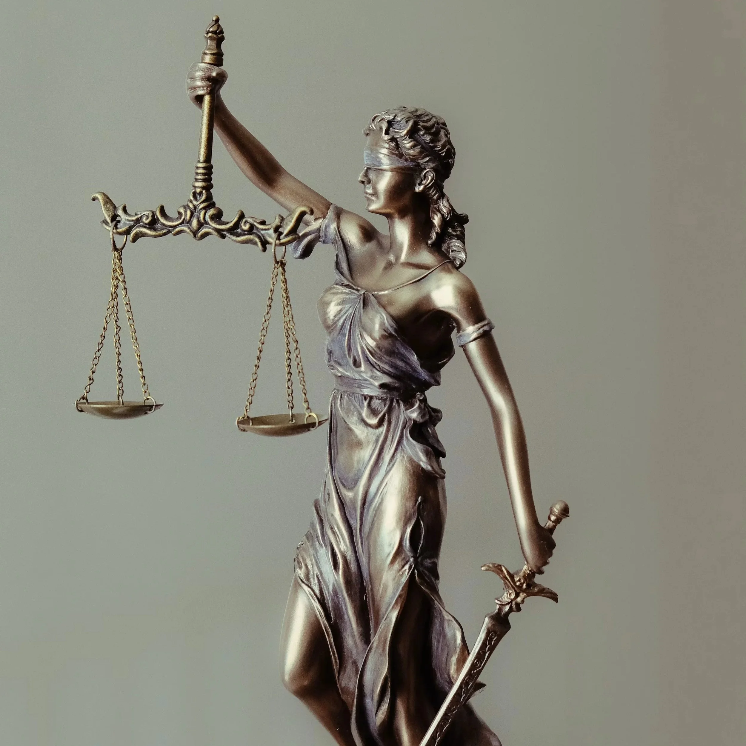 A bronze statue of Lady Justice holding scales in her left hand and a sword in her right hand, wearing a blindfold.