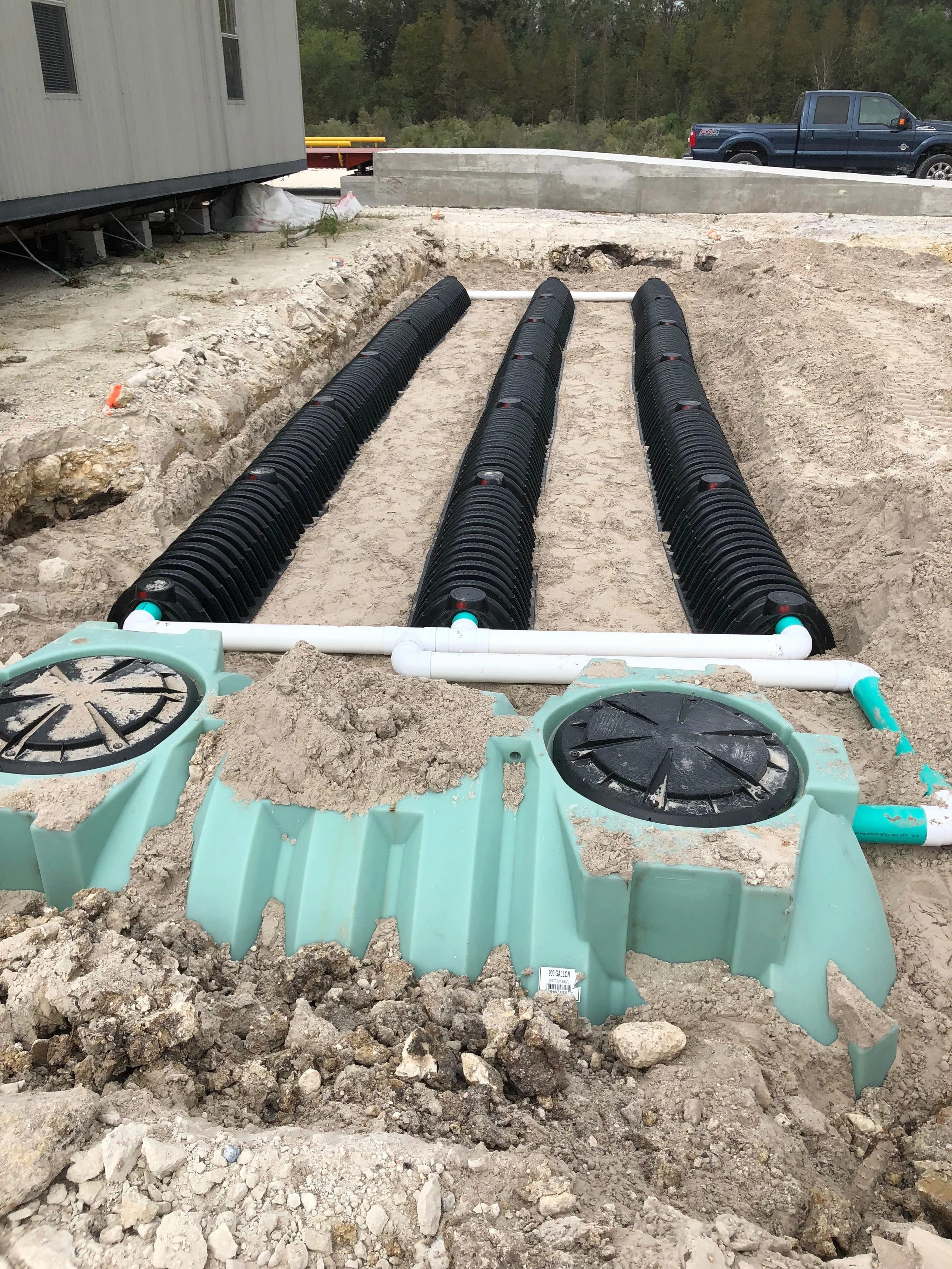 Underground utility pipes for water or sewer system installation at a construction site with soil and rocks surrounding the area.
