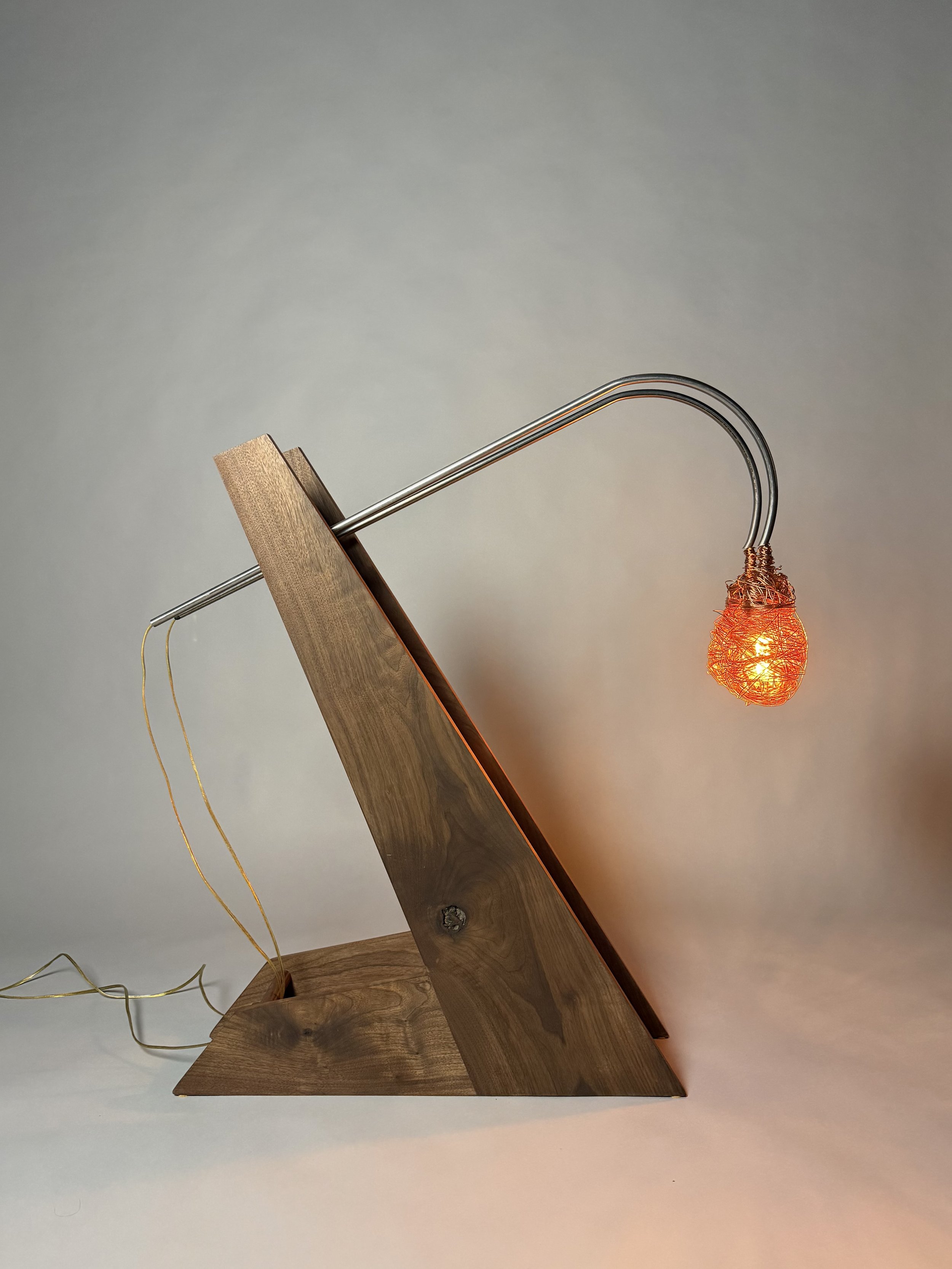 A wooden standing lamp with a curved metal arm and a woven lampshade emitting orange light.
