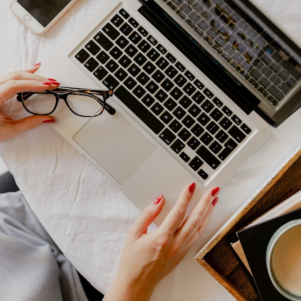 glasses resting on a Mac laptop while someone types
