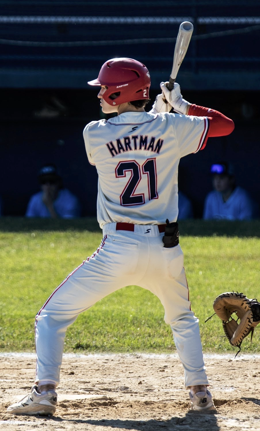 Baseball player wearing a red helmet and white jersey with the name "HARTMAN" and the number 21, standing in batting stance with a bat, on the field.